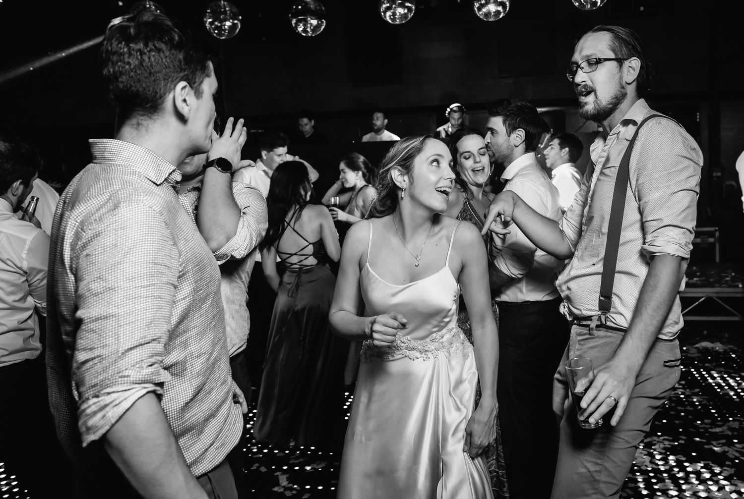 Black and white photo of bride and guests dancing at an elegant wedding reception.