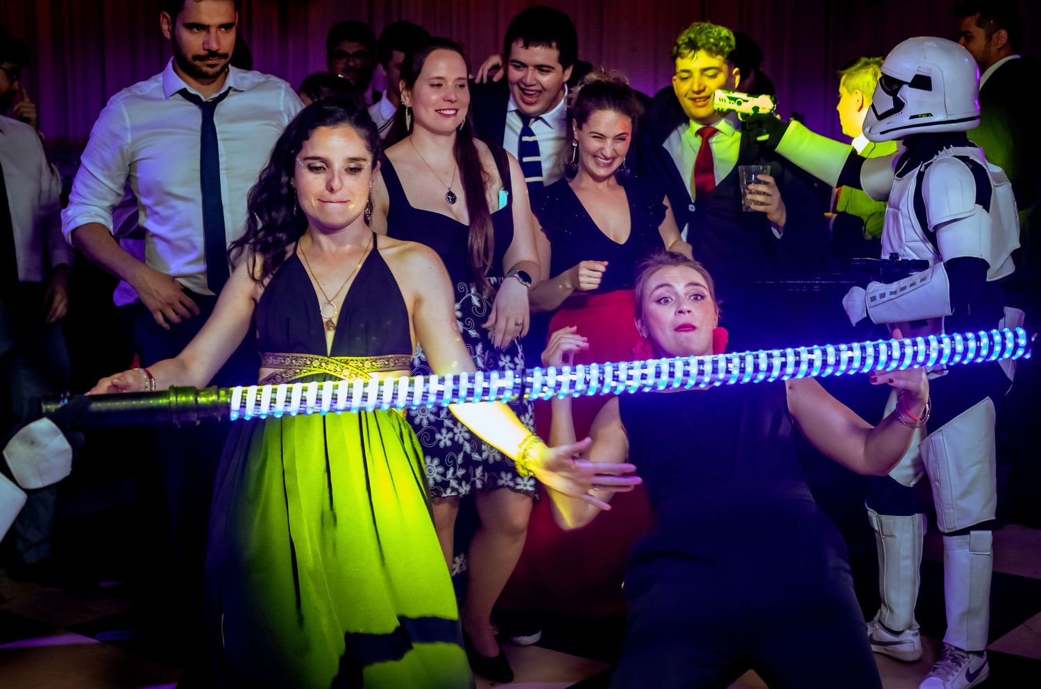 Guests dance at a Star Wars themed wedding reception with a glowing lightsaber limbo bar.