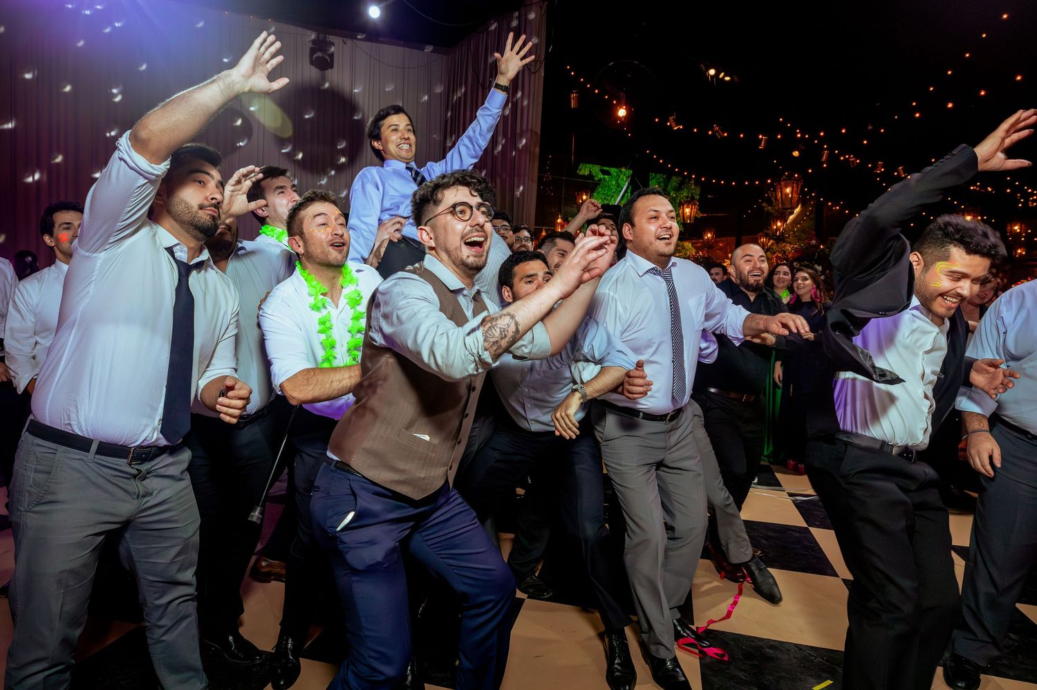 Excited group of men dancing and celebrating energetically on a wedding reception dance floor.