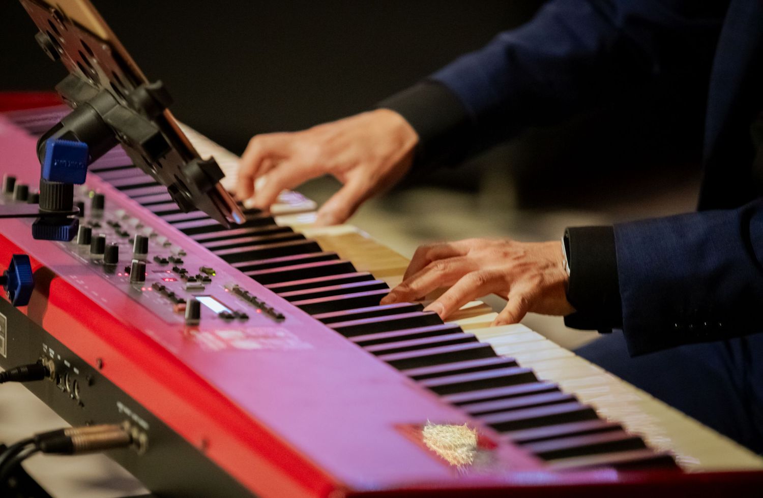 Musician plays a red Nord keyboard synthesizer during a live wedding reception performance.