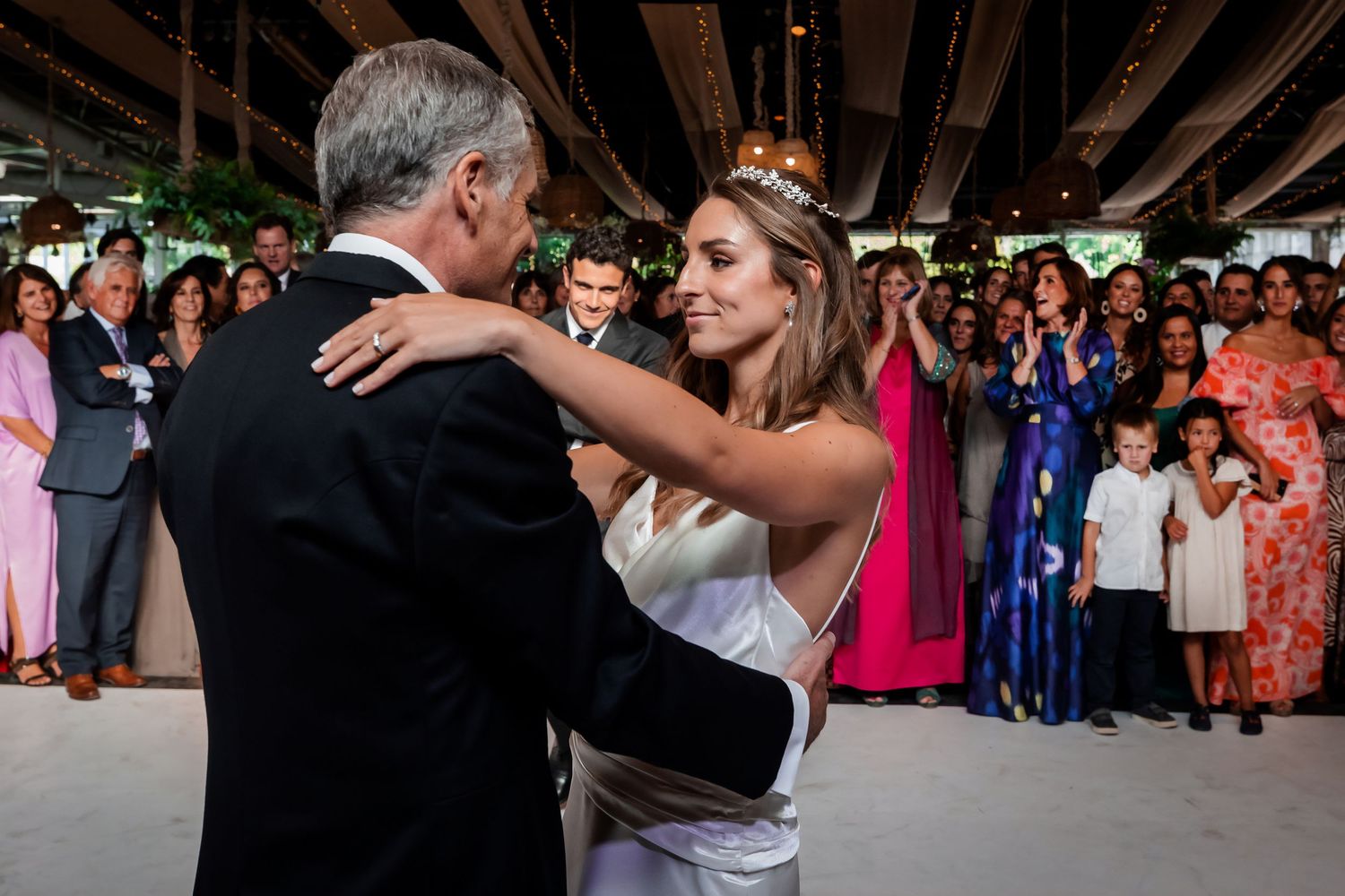 Bride shares an emotional father-daughter dance surrounded by applauding wedding guests.