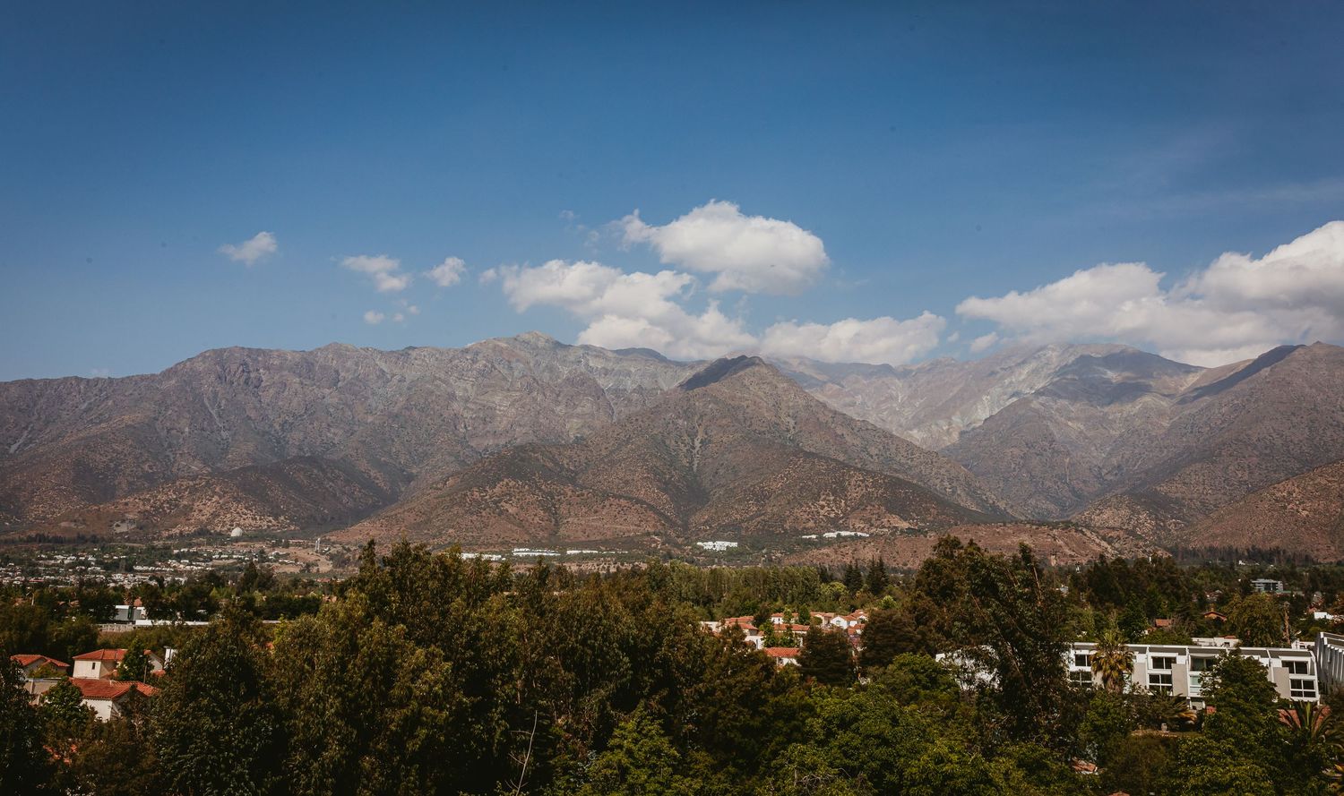 Panoramic view of Santiago Chile with Andes mountains under blue sky.