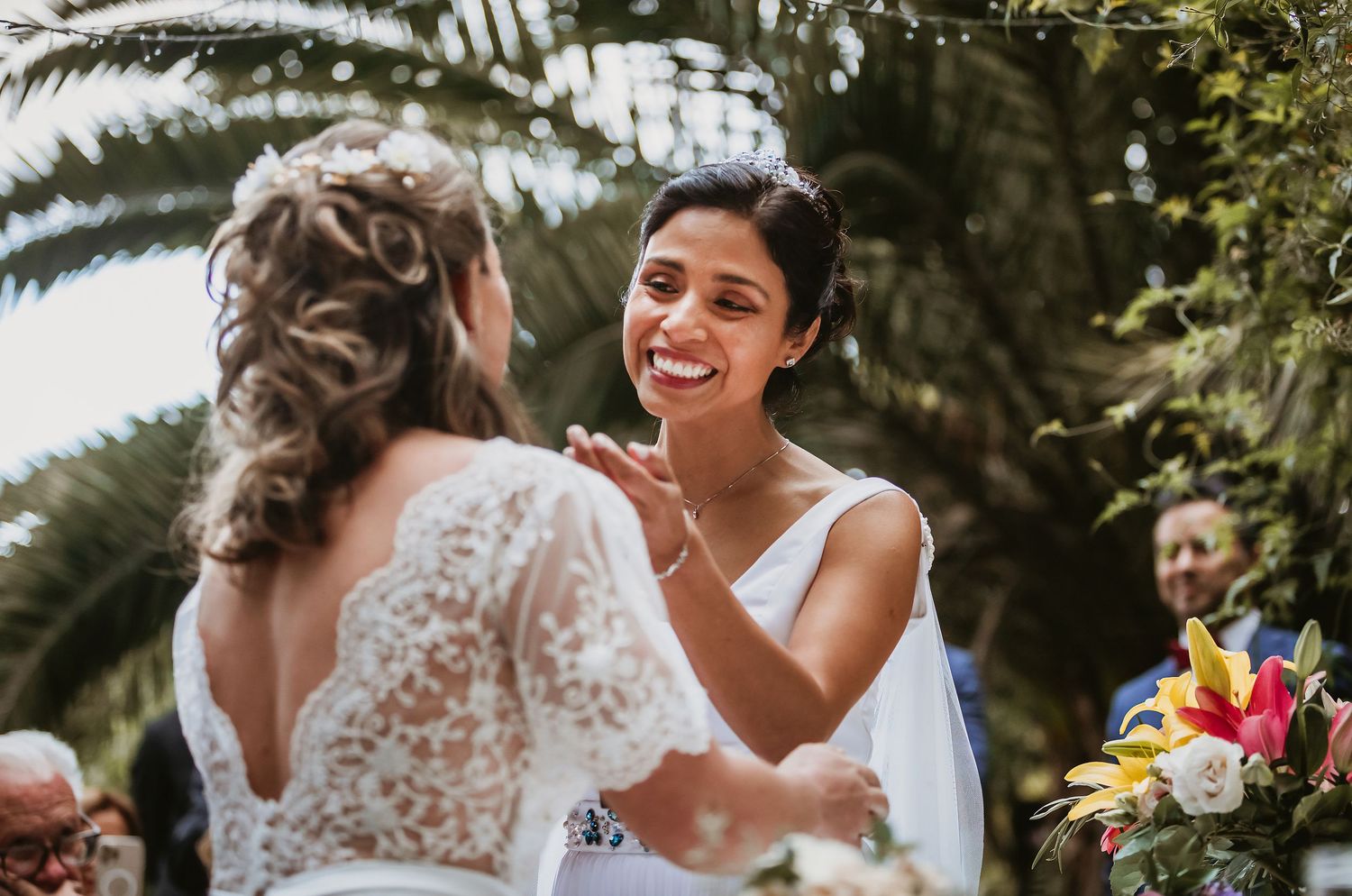 Two brides share a joyful moment during their outdoor wedding ceremony.