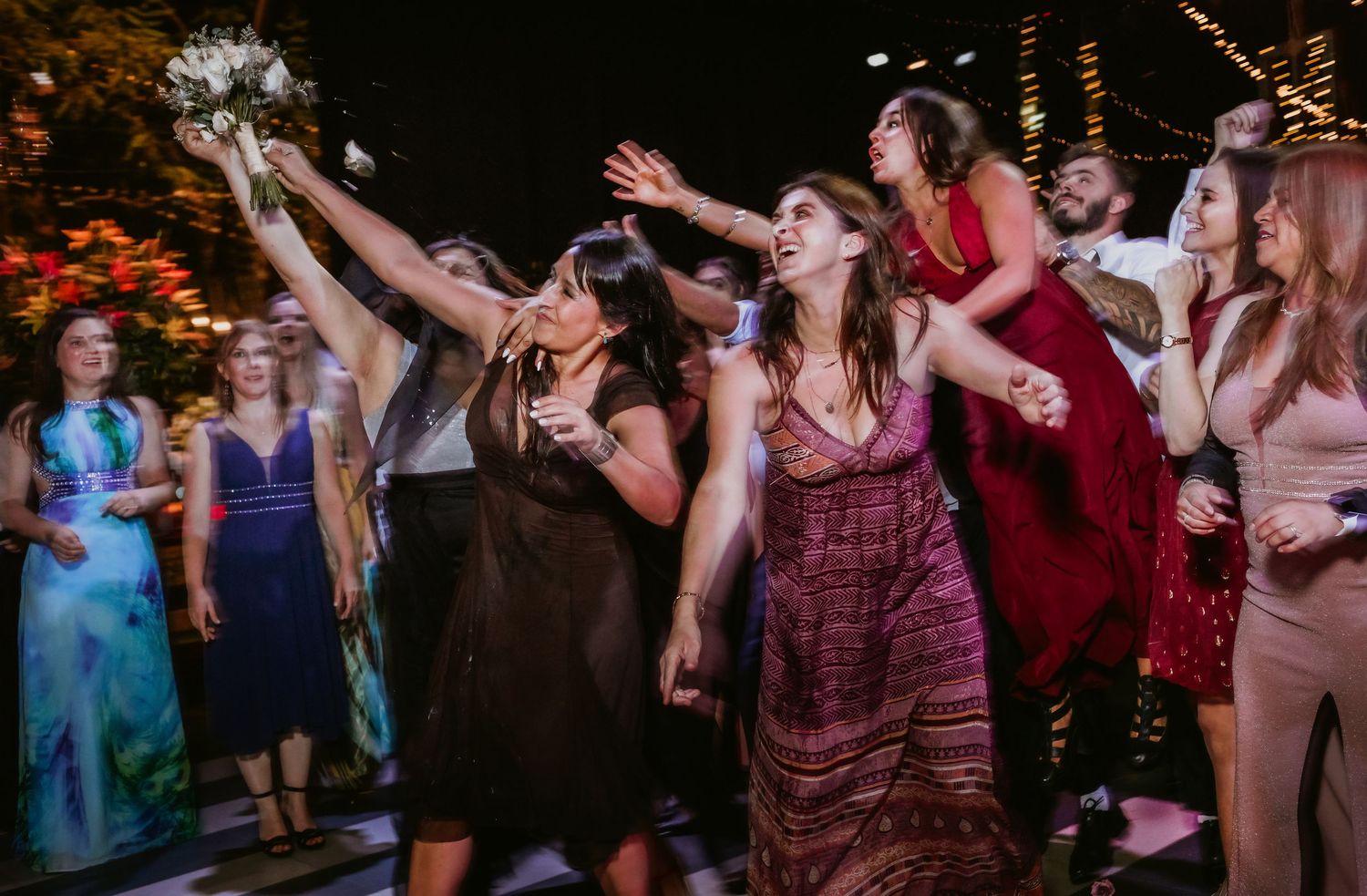 Guests eagerly reach for the bouquet during the traditional wedding bouquet toss.