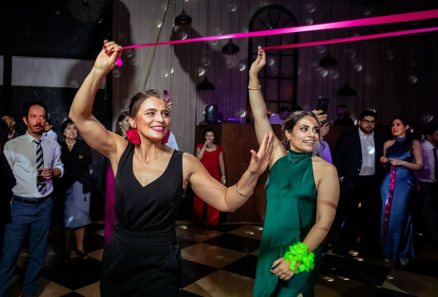 Two women dance with colorful ribbons at an elegant wedding reception celebration.