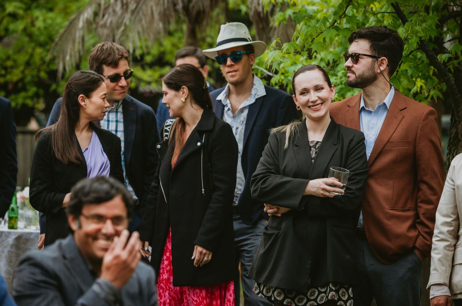 Group of elegantly dressed guests socializing outdoors at a garden party event.
