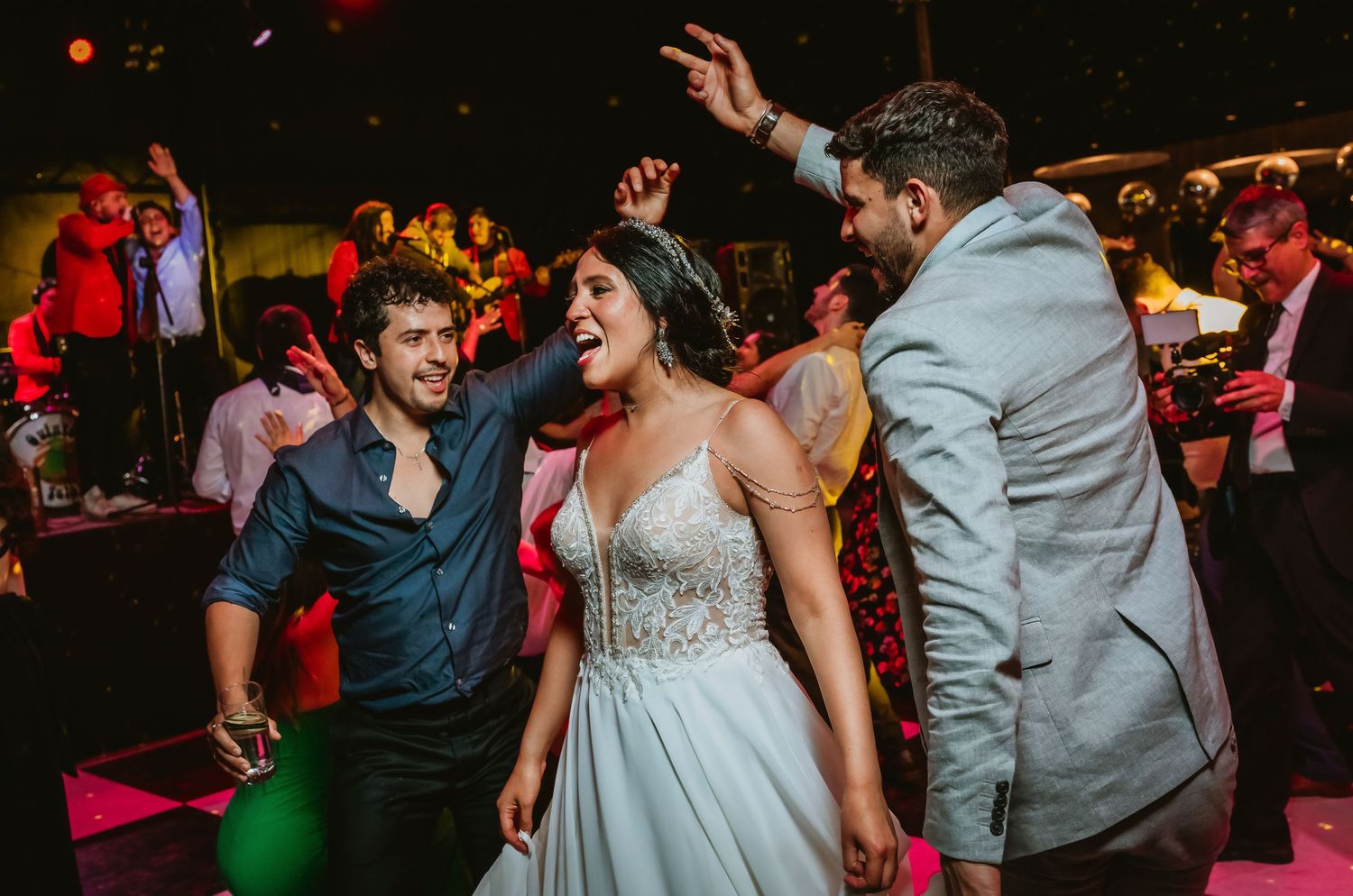 Bride in white gown dancing with guests at a vibrant wedding reception party.