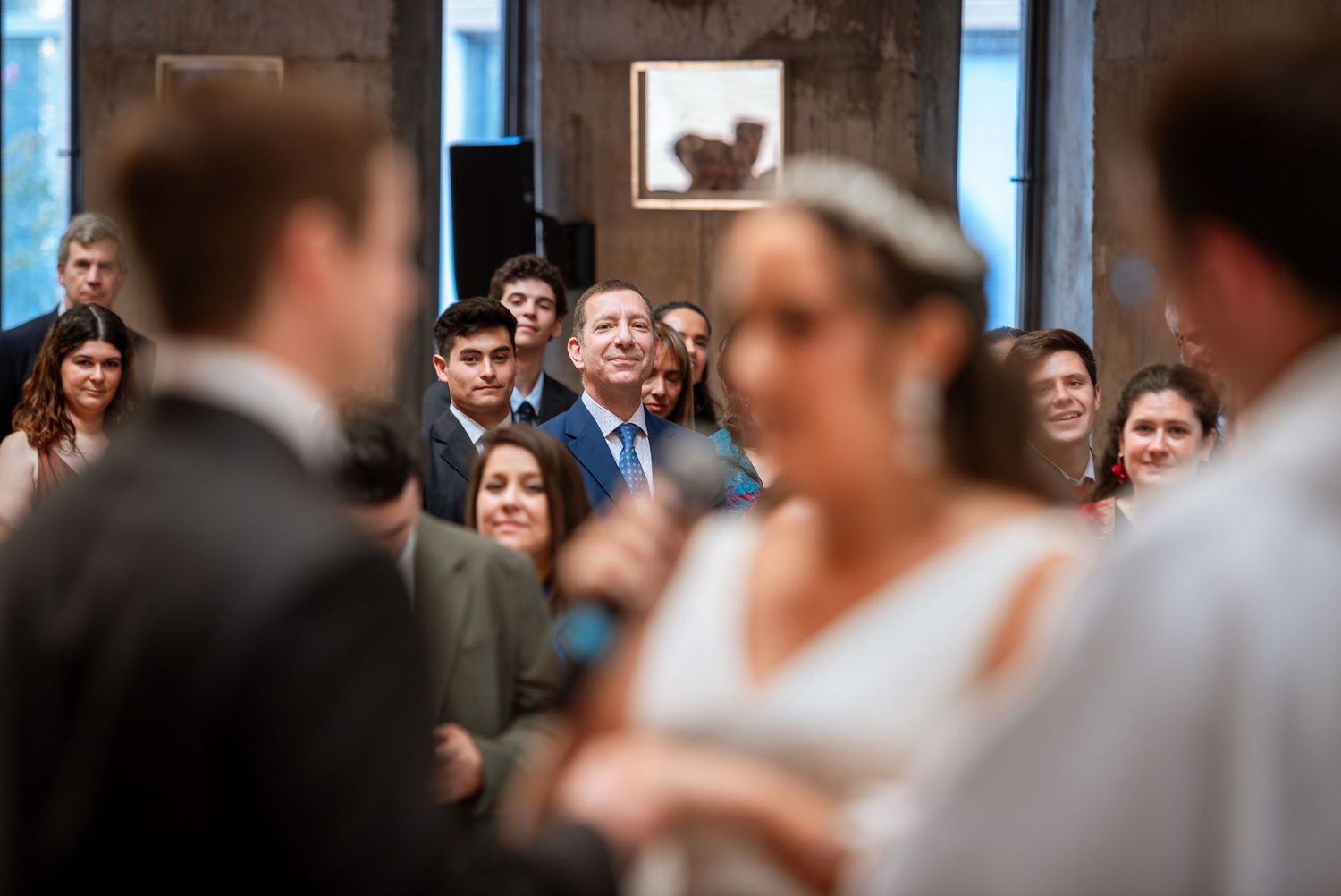 Wedding guests smile and watch the ceremony as the bride and groom exchange vows at the altar.