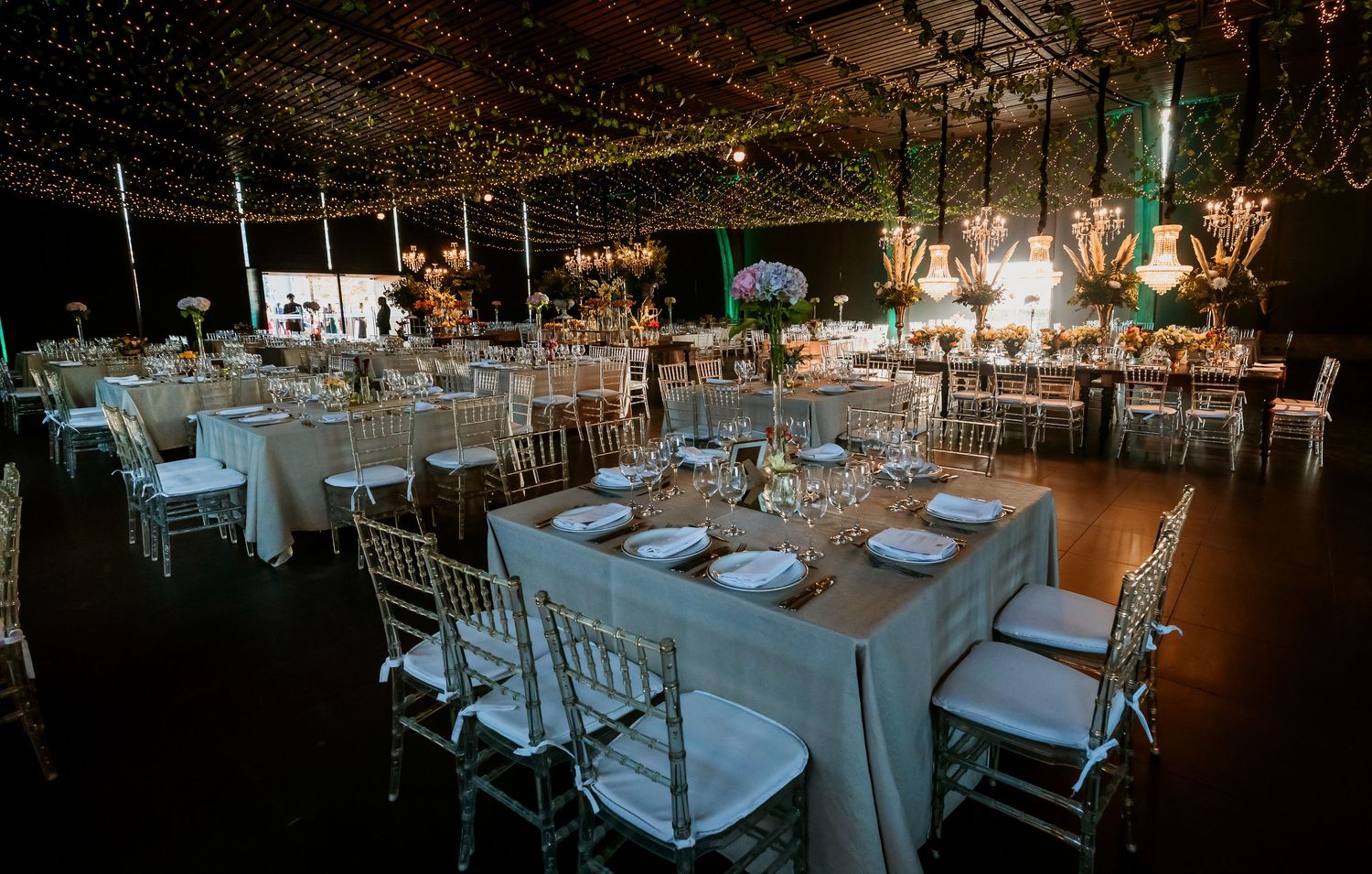 Elegant wedding banquet hall with round tables, chiavari chairs and warm string lights.