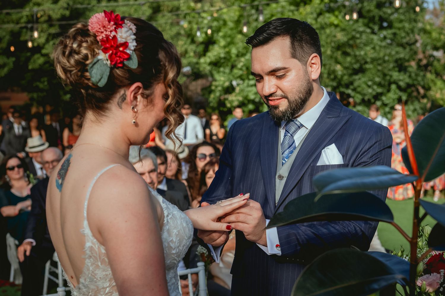 Groom places wedding ring on bride's finger during intimate outdoor garden ceremony.