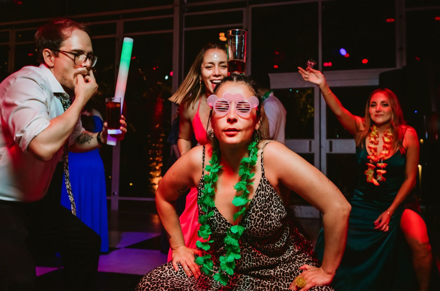 Women dancing and celebrating at a vibrant party with glow sticks and festive accessories.