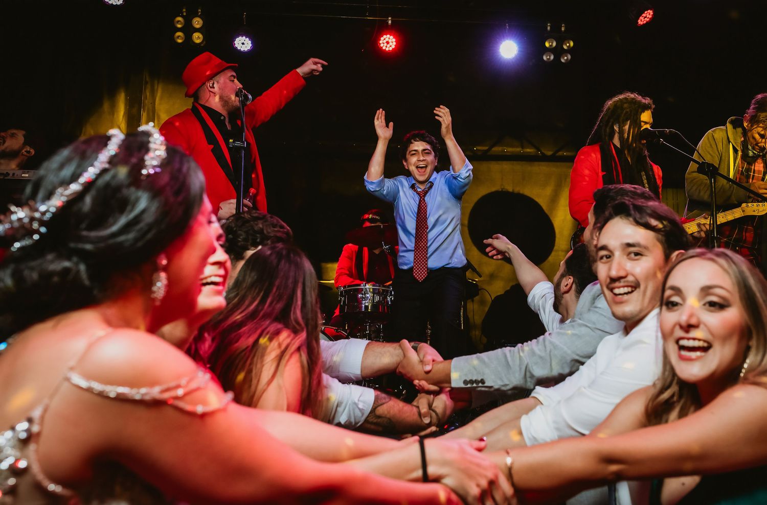 Guests dancing joyfully at a lively wedding reception with a live band performing on stage.