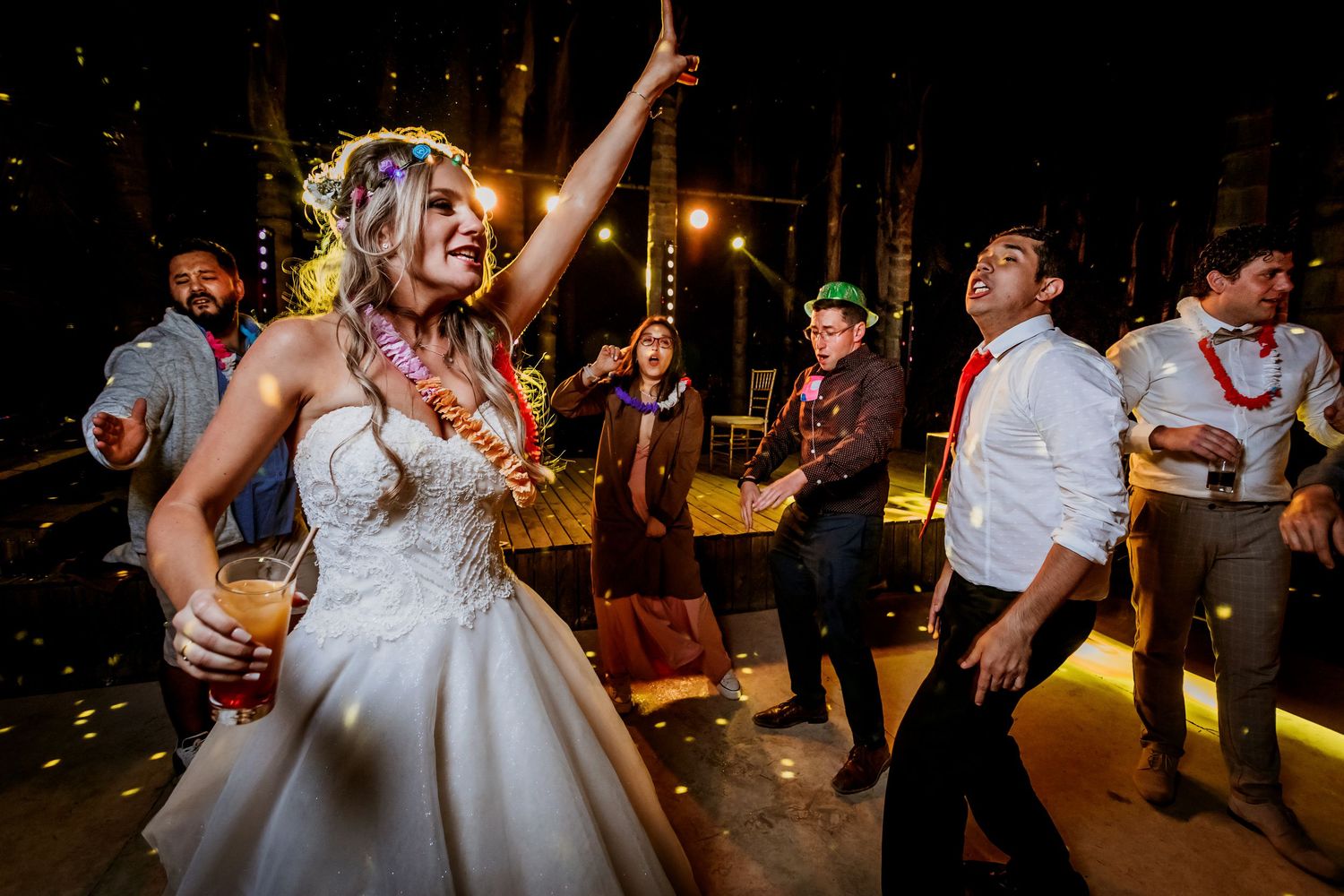 Joyful bride dancing with wedding guests outdoors at a lively nighttime reception.