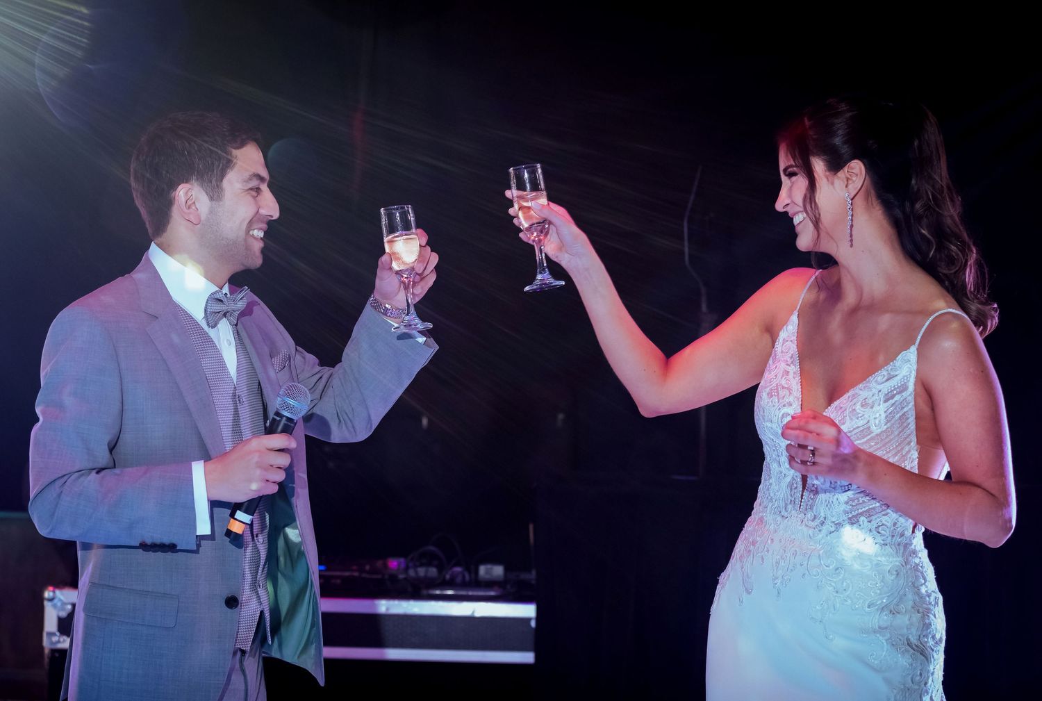 A bride and groom in elegant attire toasting with champagne glasses at their wedding reception.