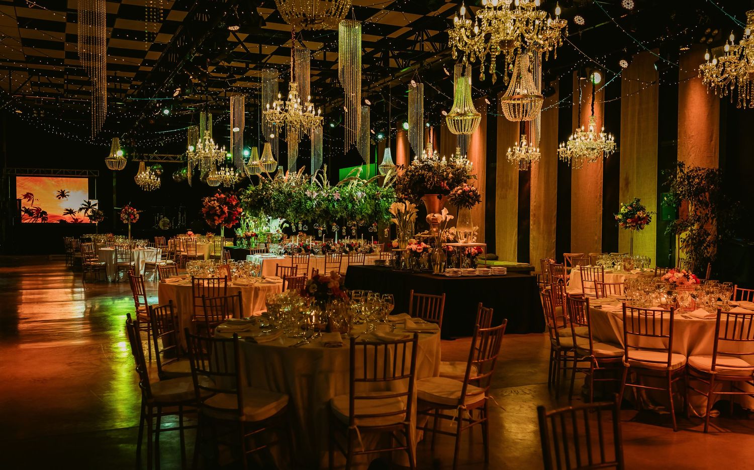 Luxurious wedding reception hall adorned with crystal chandeliers, round tables, and lush floral centerpieces.
