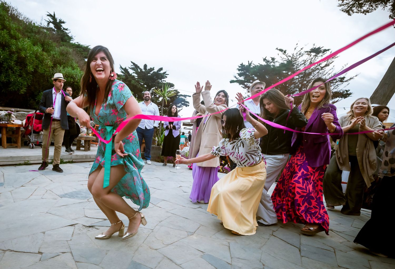 Wedding guest dances energetically with colorful ribbons during lively outdoor reception party.