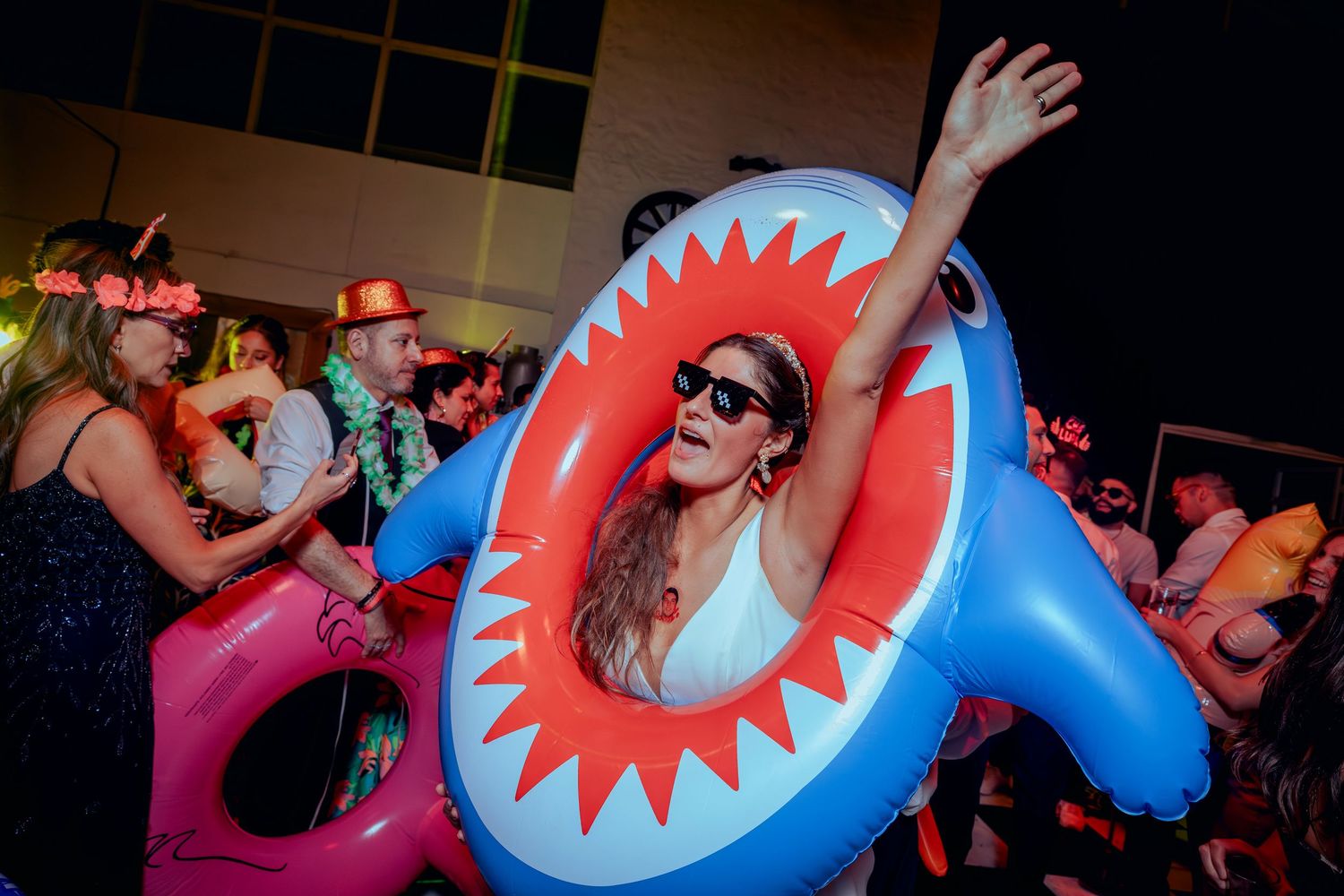 Woman dancing inside inflatable shark float at festive party celebration.