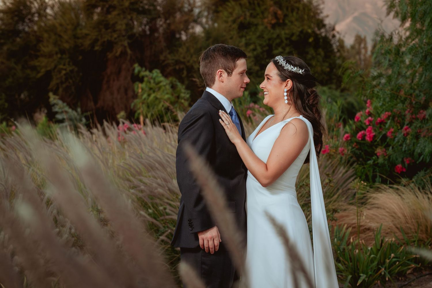 Bride and groom sharing an intimate moment face to face surrounded by lush garden foliage.
