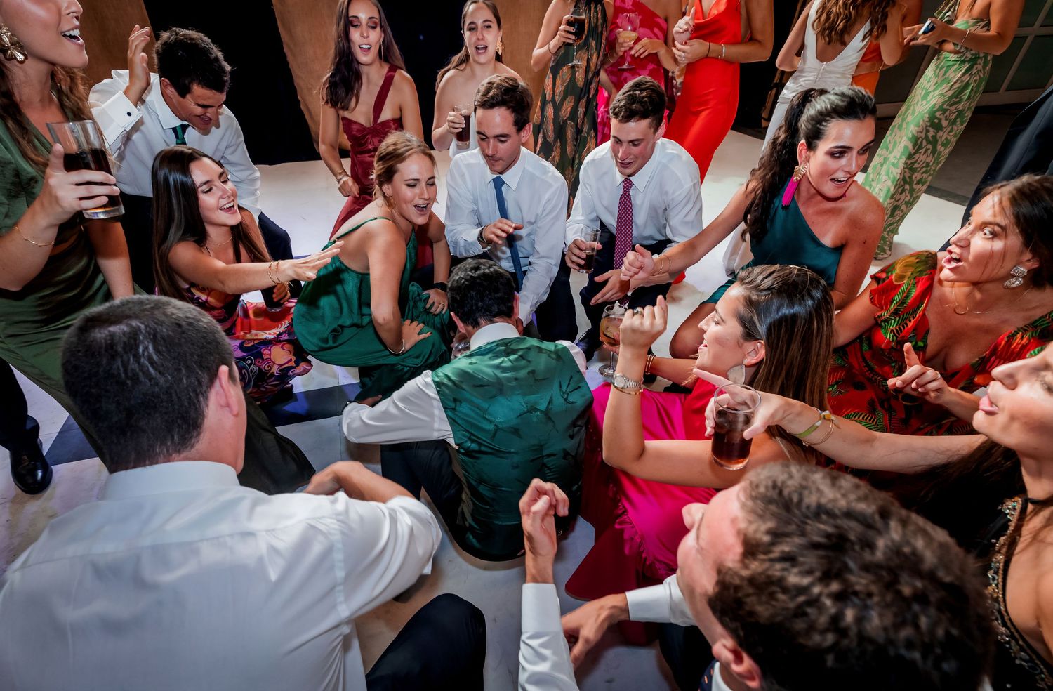 Wedding guests celebrate energetically in a lively dance circle at the reception.