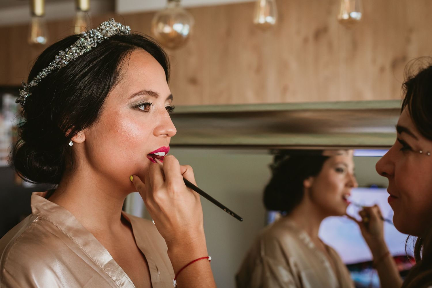 Bride getting her makeup applied by a professional artist while wearing a tiara before her wedding.
