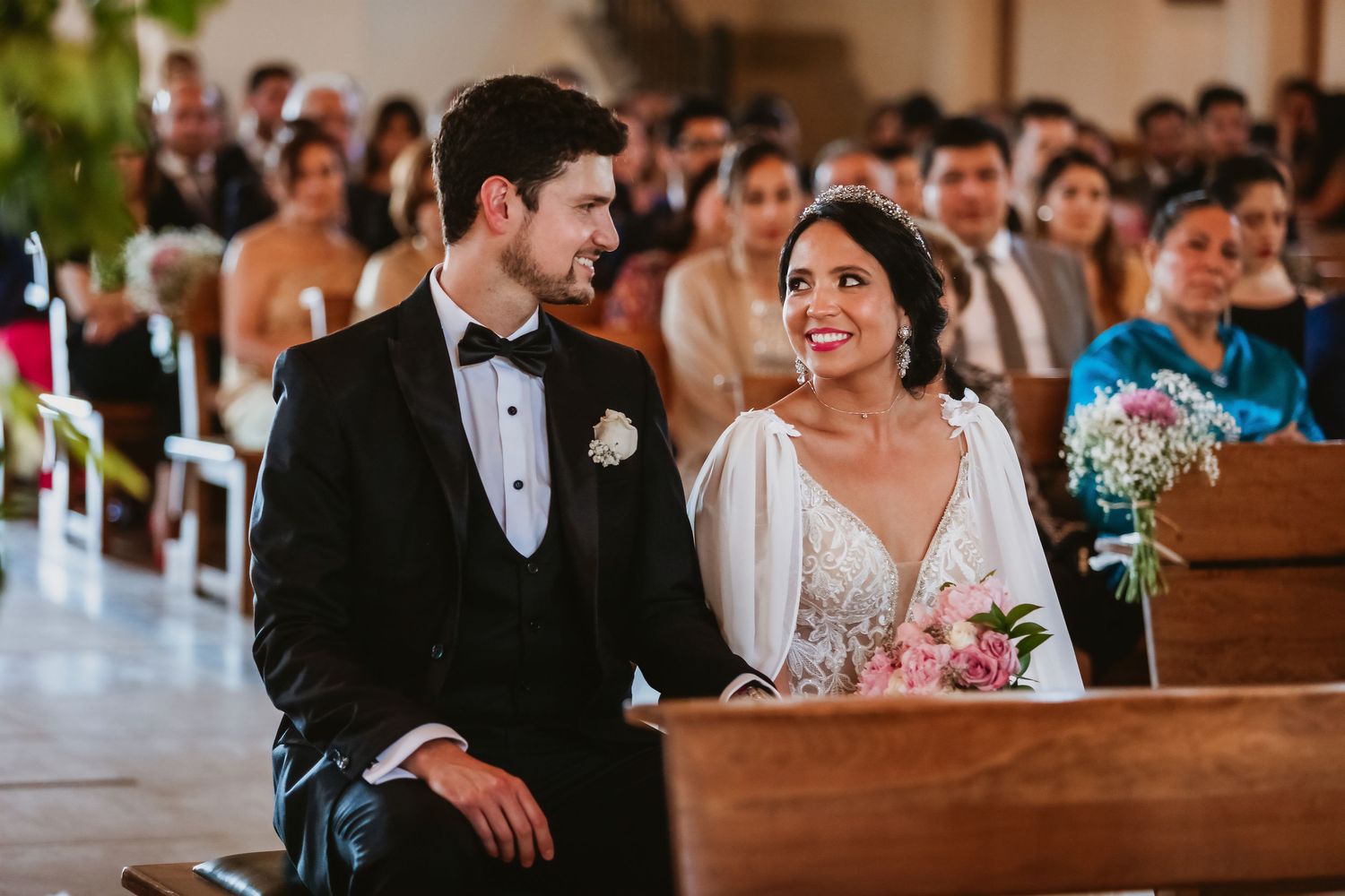 Bride and groom sharing a joyful smile during their wedding ceremony inside a beautiful church.