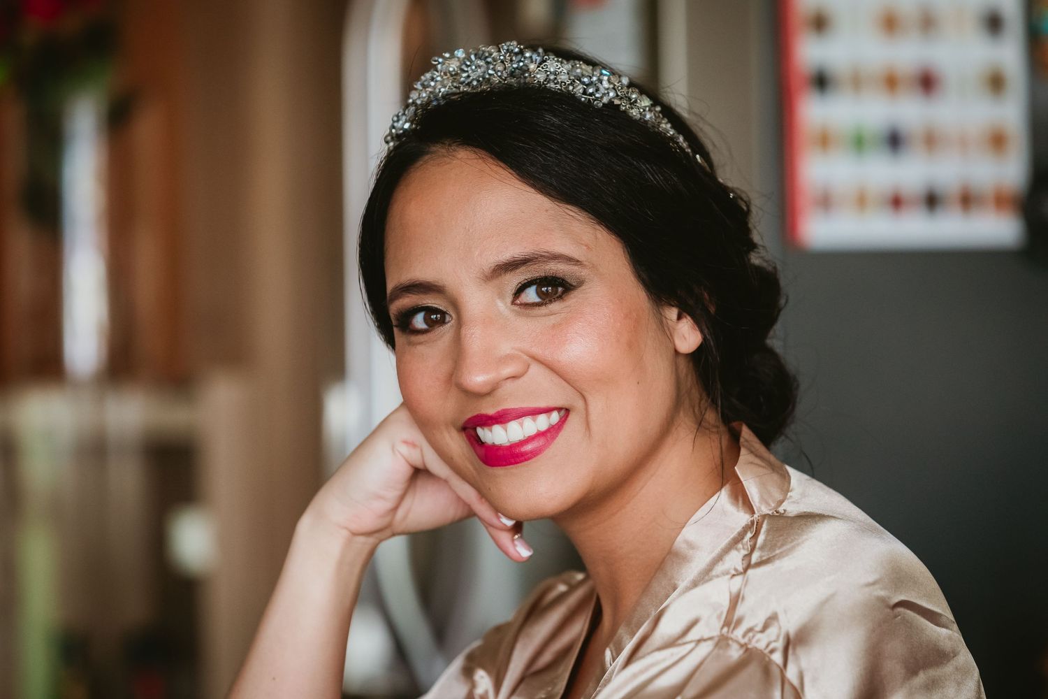 Beautiful bride smiling warmly wearing a crystal tiara and pink lipstick on her wedding morning.