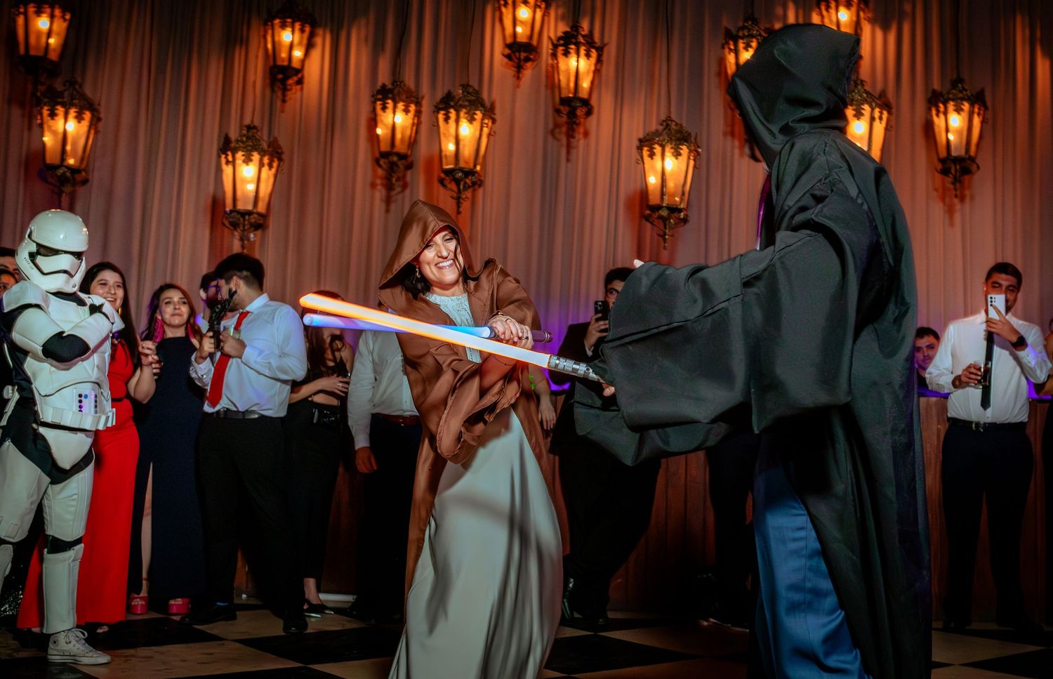 Wedding guest in Jedi costume dueling with lightsaber against Darth Vader at a reception.