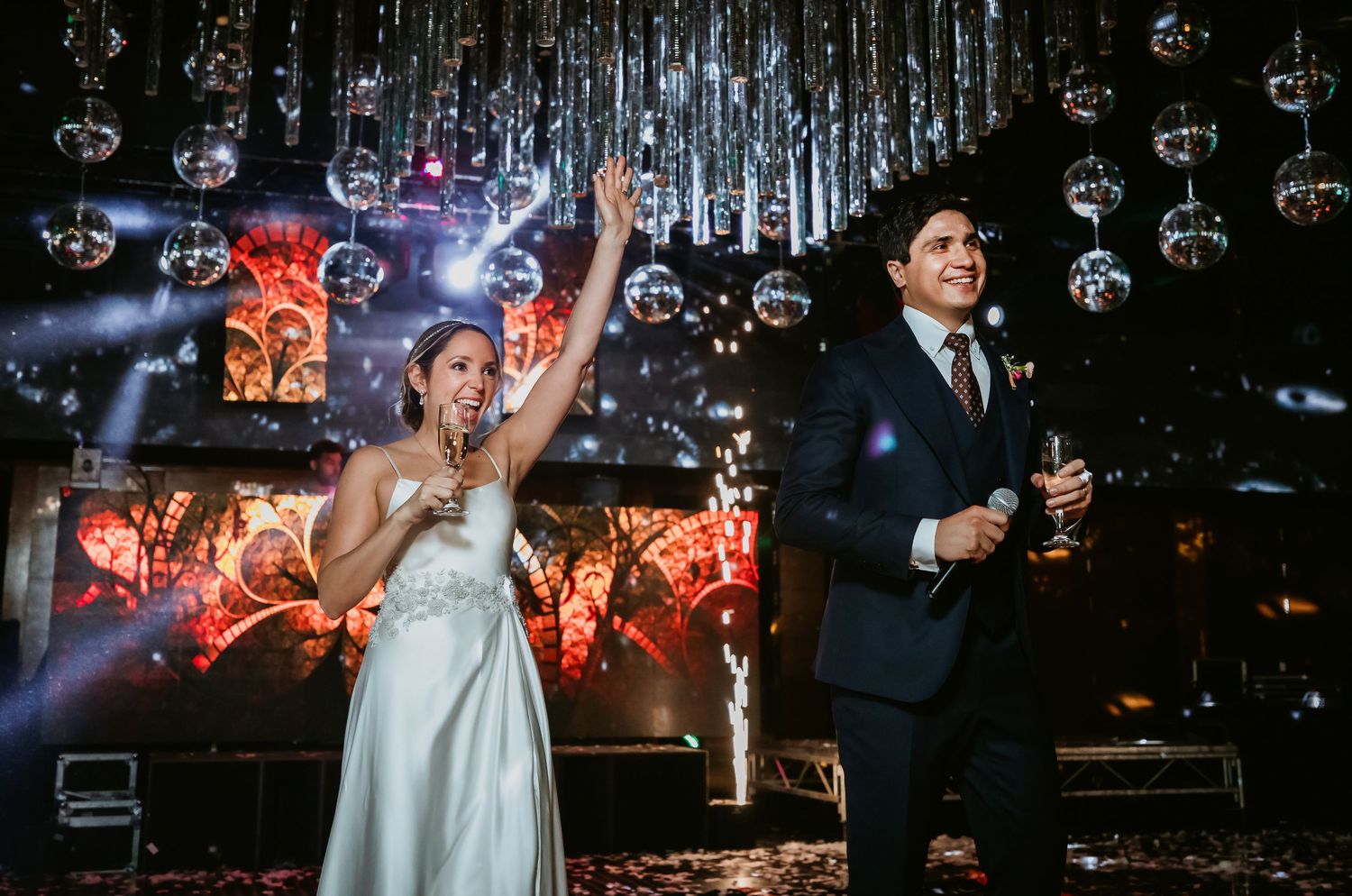 Bride and groom celebrating at a glamorous wedding reception with sparkling disco ball ceiling decor.