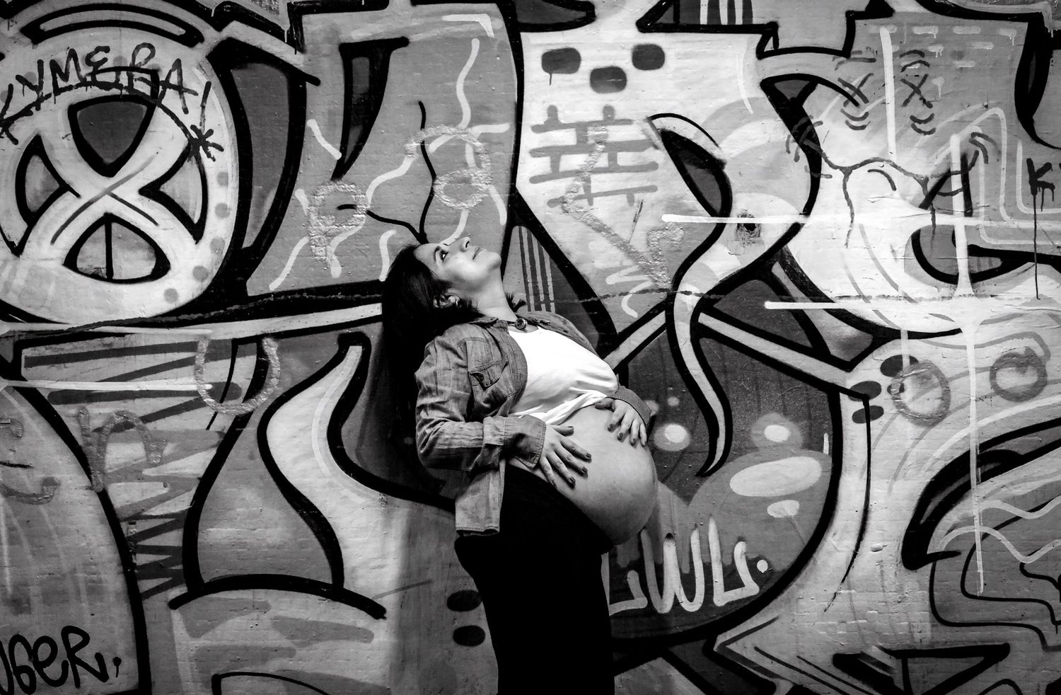 Black and white image of couple sharing a romantic kiss against a bold graffiti wall.