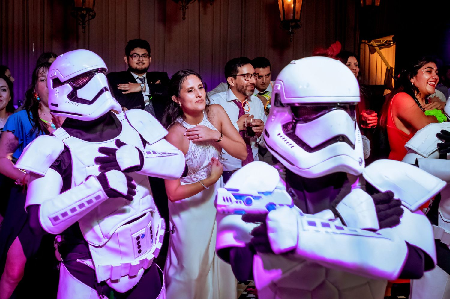 A bride dances joyfully between two Star Wars Stormtroopers at her wedding reception.