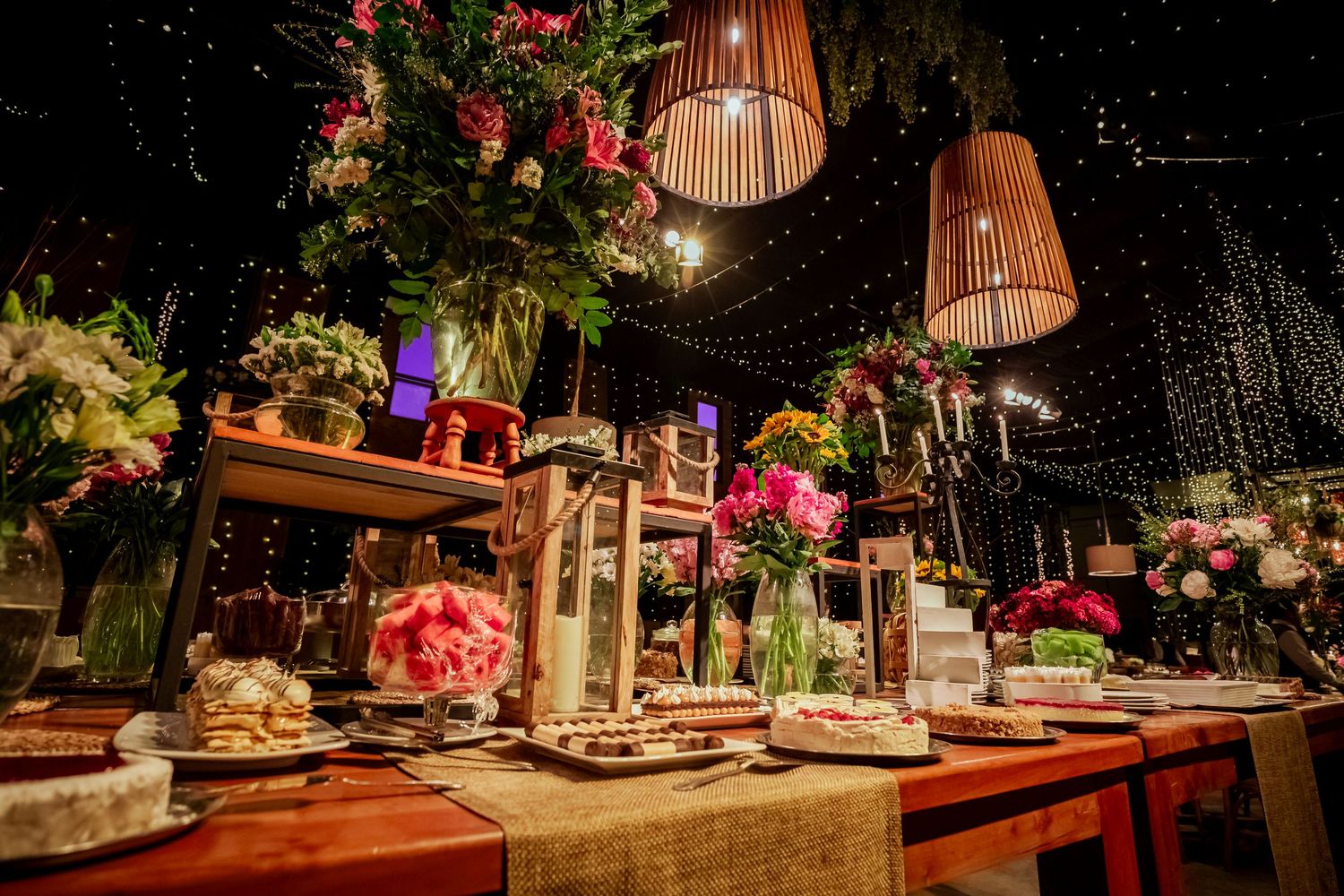 Elegant wedding reception table adorned with pink floral arrangements and hanging lanterns.