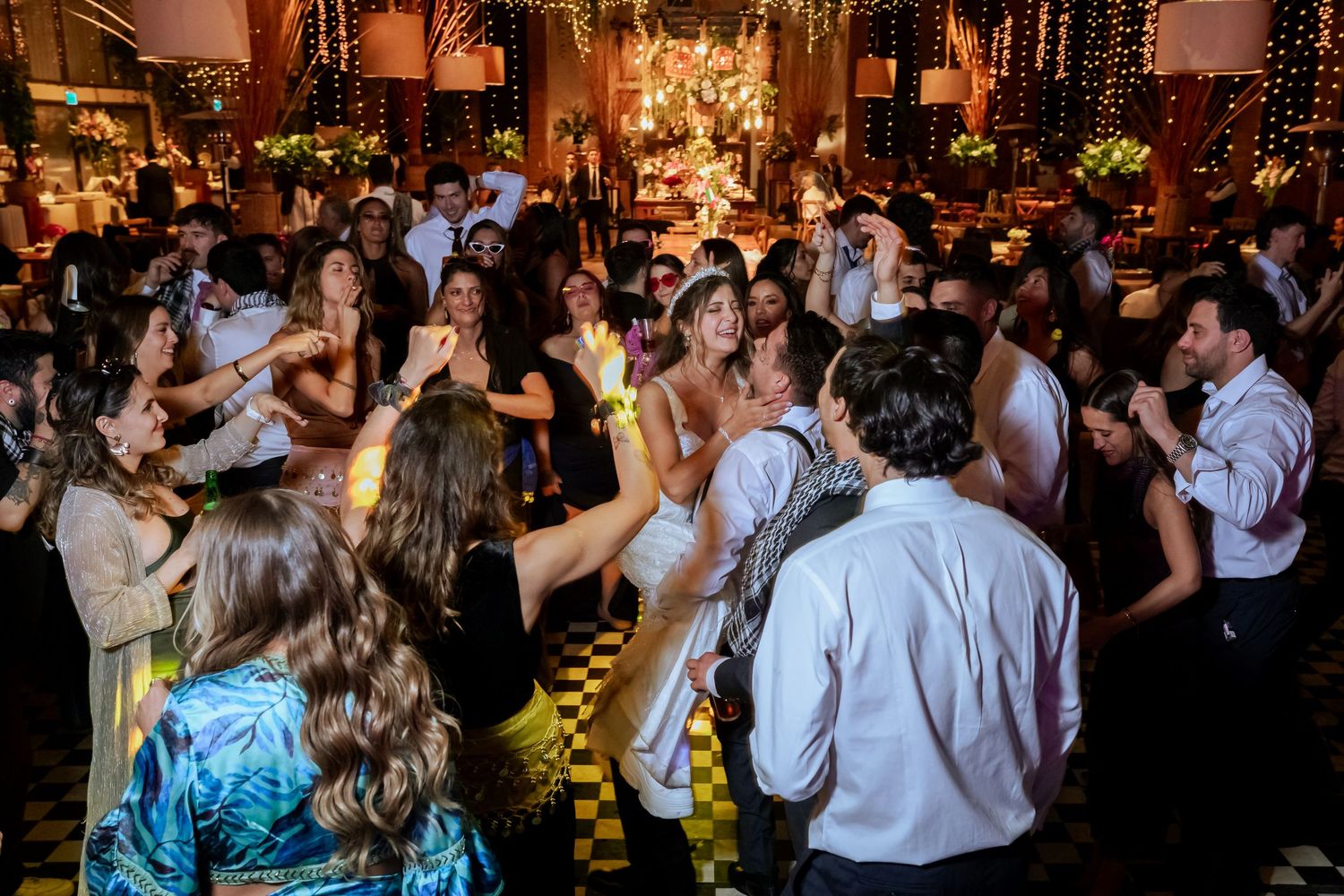 Bride and groom share a joyful dance surrounded by celebrating guests at their wedding reception.
