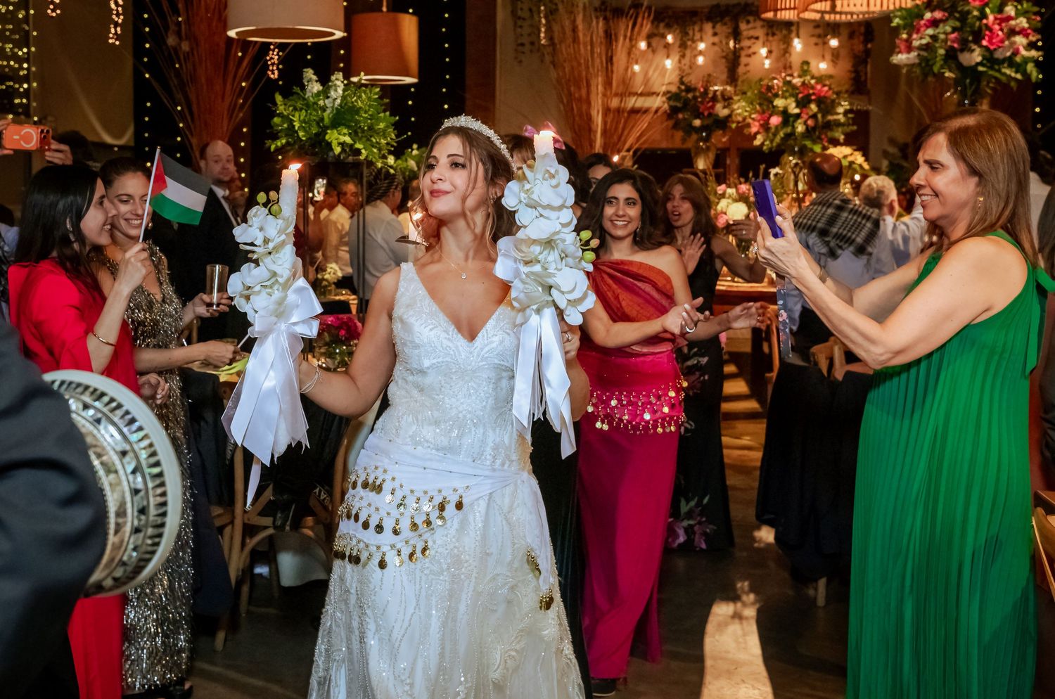 Bride dancing with floral candles as guests celebrate at a colorful wedding reception.