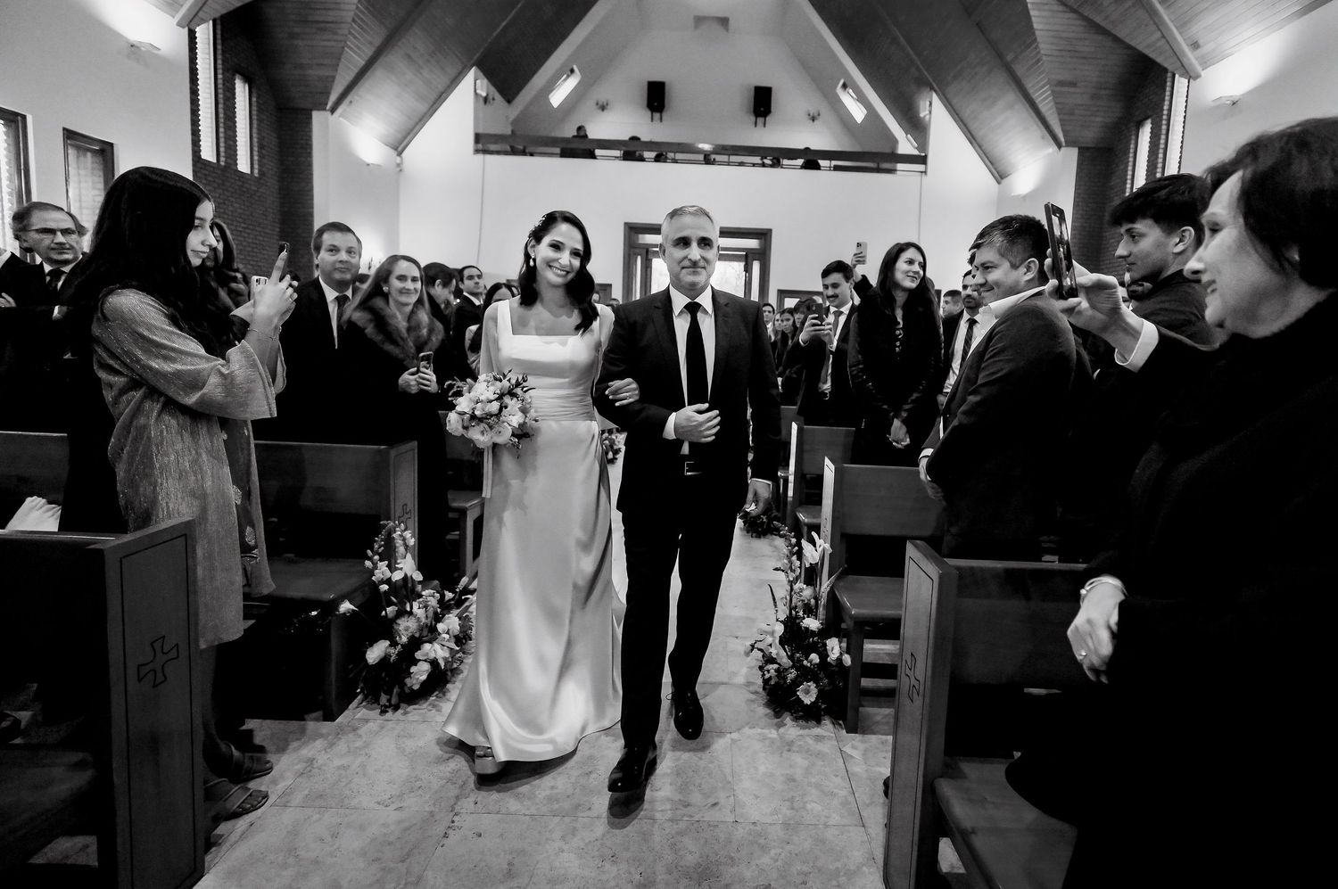 Black and white photo of a bride and groom walking down the church aisle at their wedding ceremony.