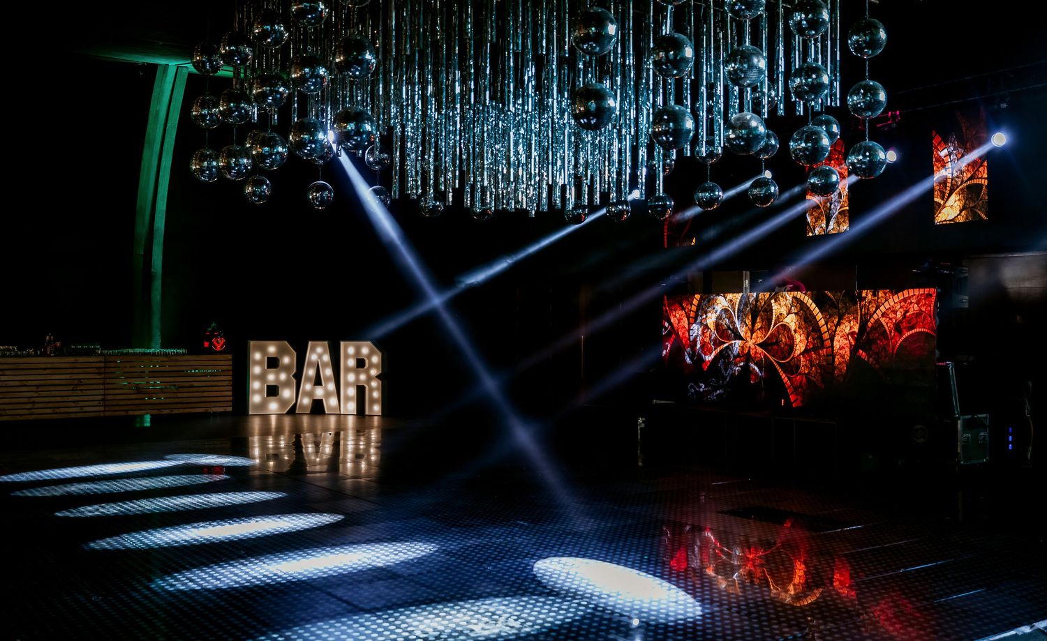 Elegant dark event venue with illuminated BAR sign and dramatic stage lighting.