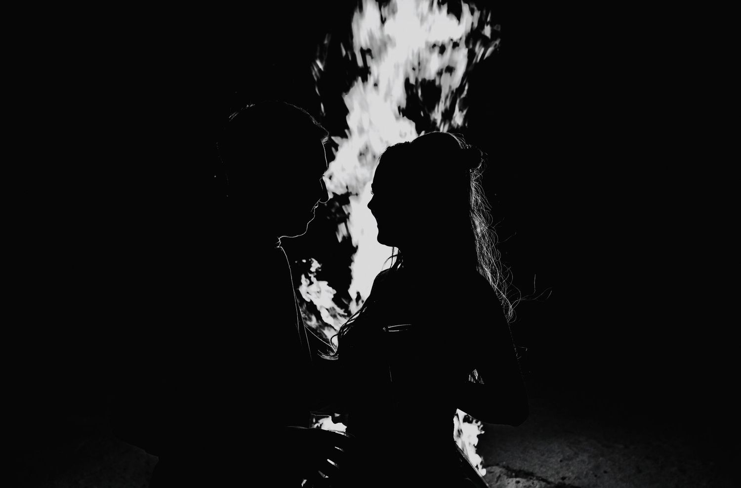 Dramatic black and white silhouette of person surrounded by fire at night.