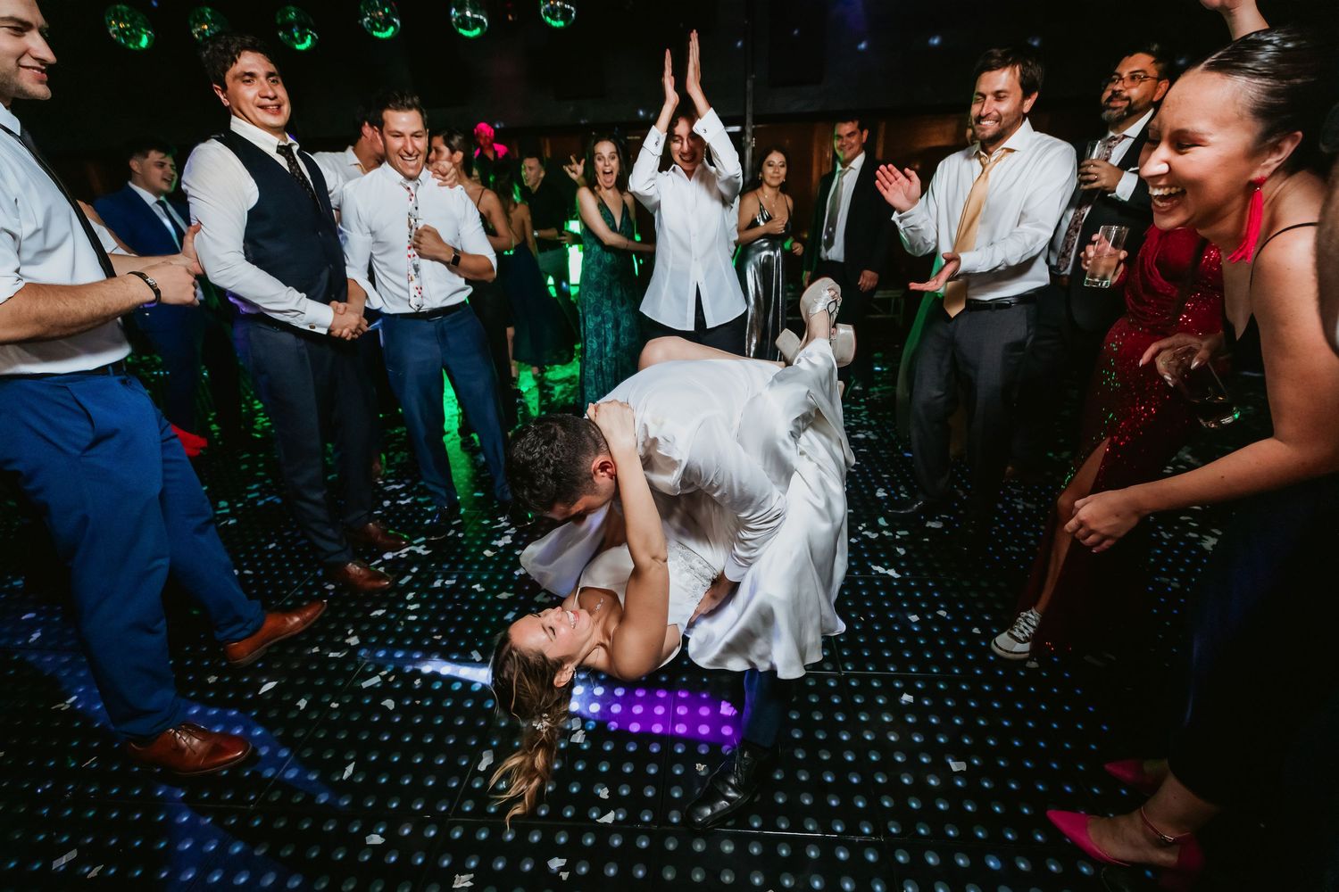 Groom dipping bride dramatically on a sparkling dance floor at a festive wedding reception.