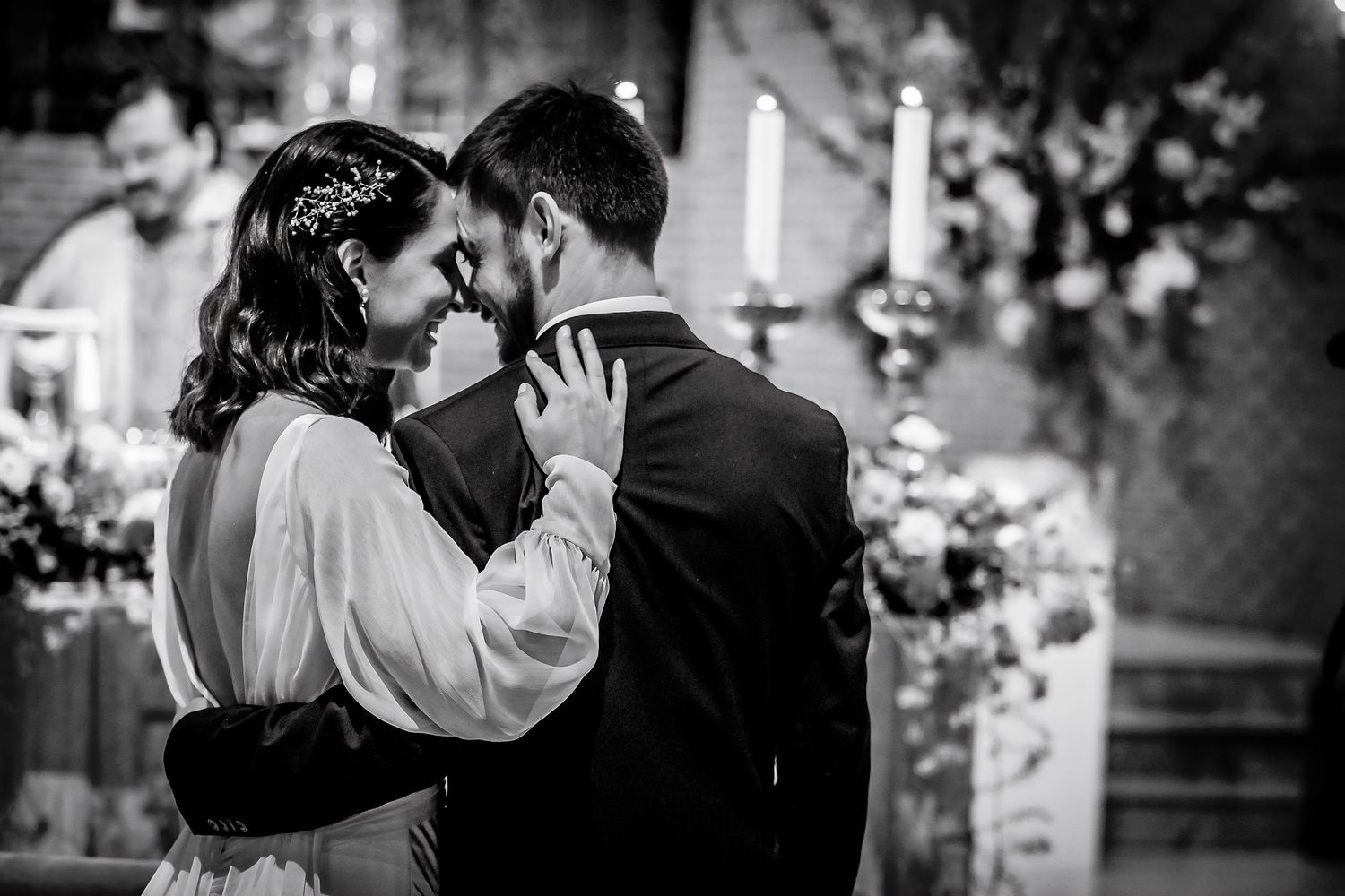 Black and white photo of a bride and groom sharing an intimate moment at the altar during their wedding ceremony.
