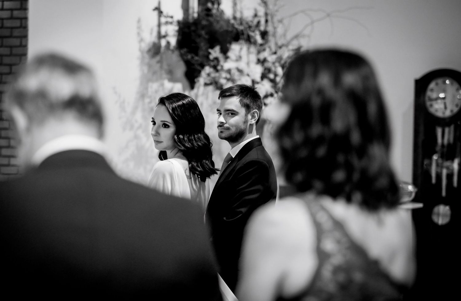 Black and white wedding ceremony photo of bride and groom standing together indoors.