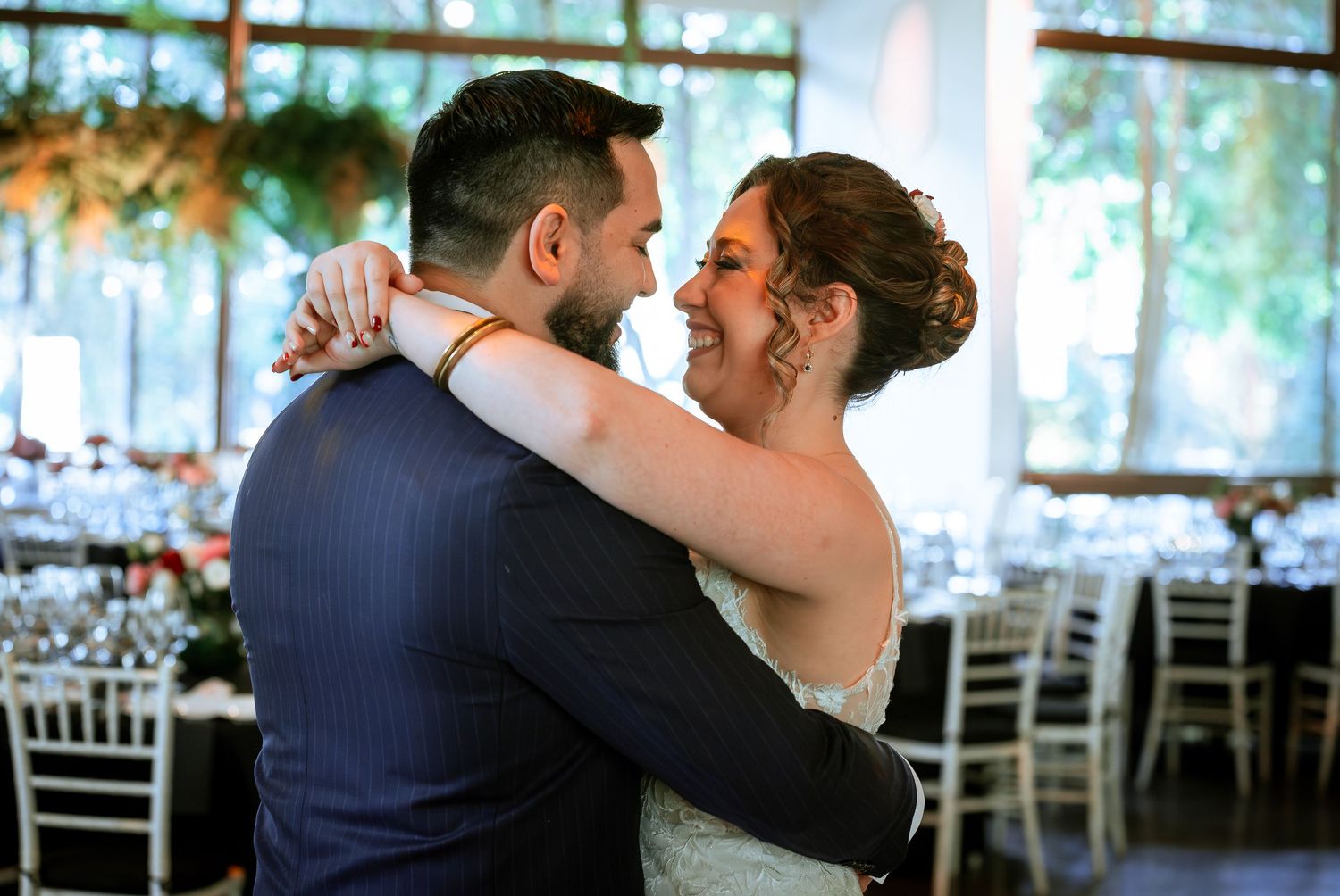 Newlyweds share tender first dance embrace in beautifully decorated wedding reception venue.