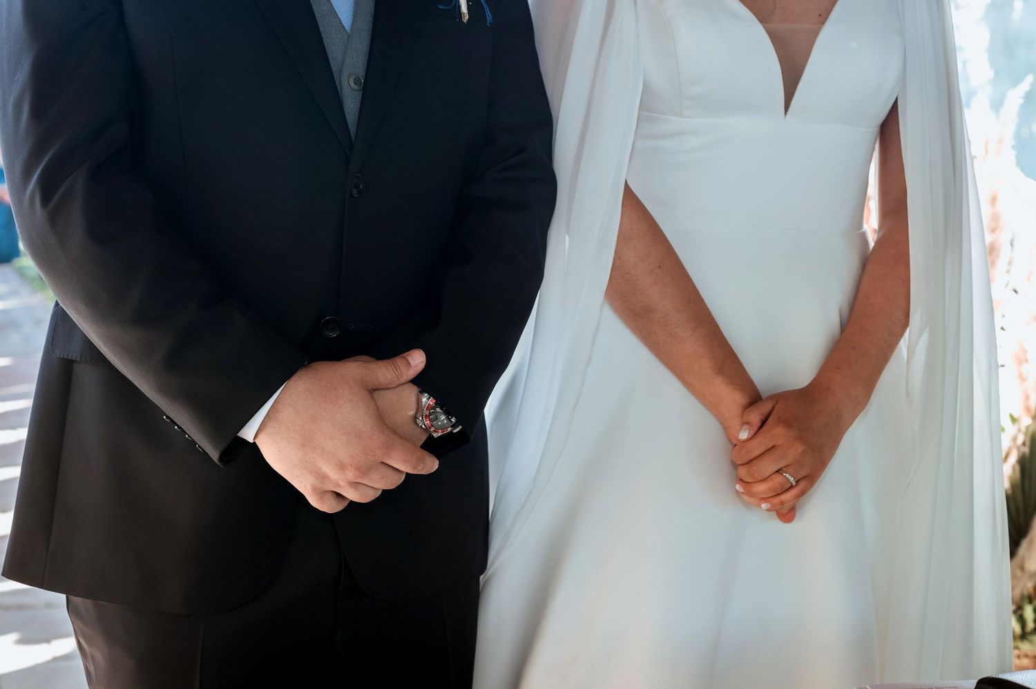 Close-up of bride and groom holding hands during wedding ceremony.