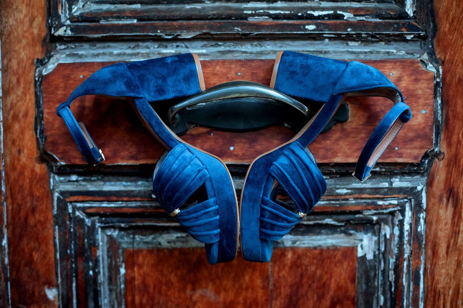 Blue suede peep-toe high heel shoes displayed on rustic wooden decorative panel.