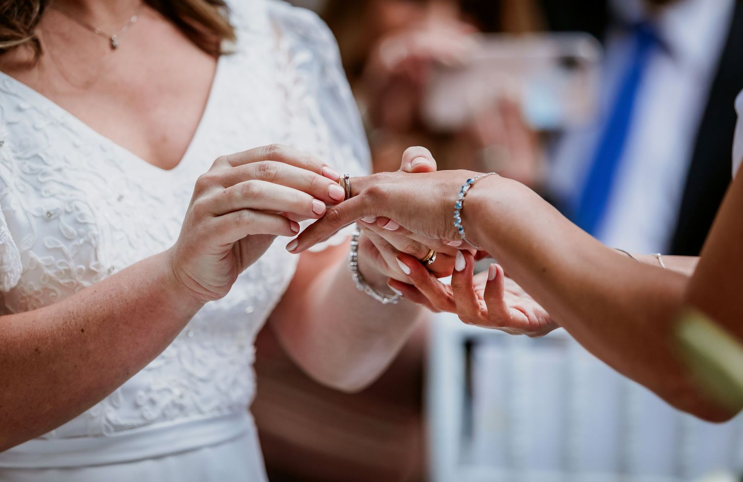 Close-up of two brides exchanging wedding rings during their marriage ceremony.