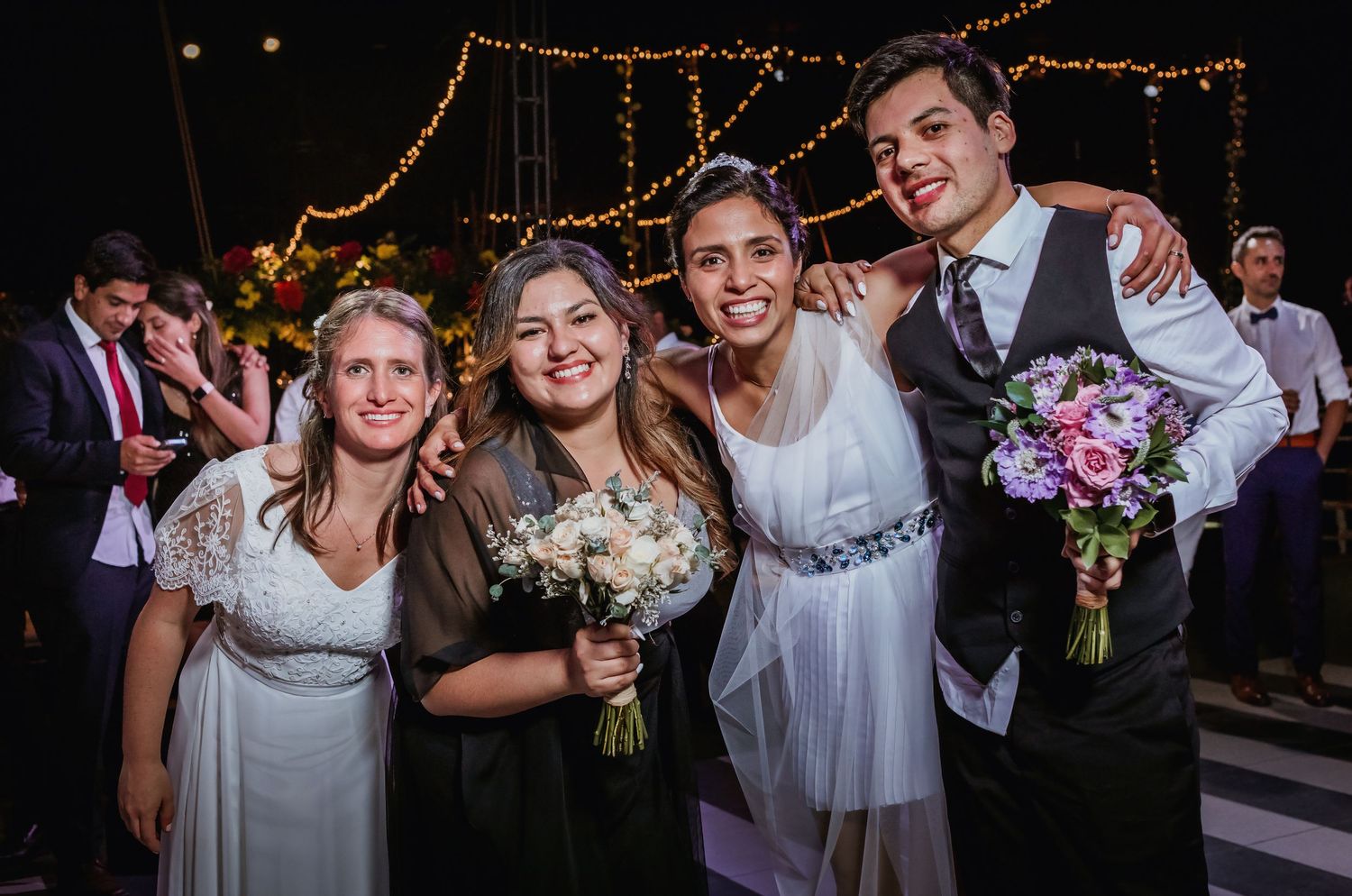 Bride and groom pose with bouquet winners for a happy wedding reception photo.