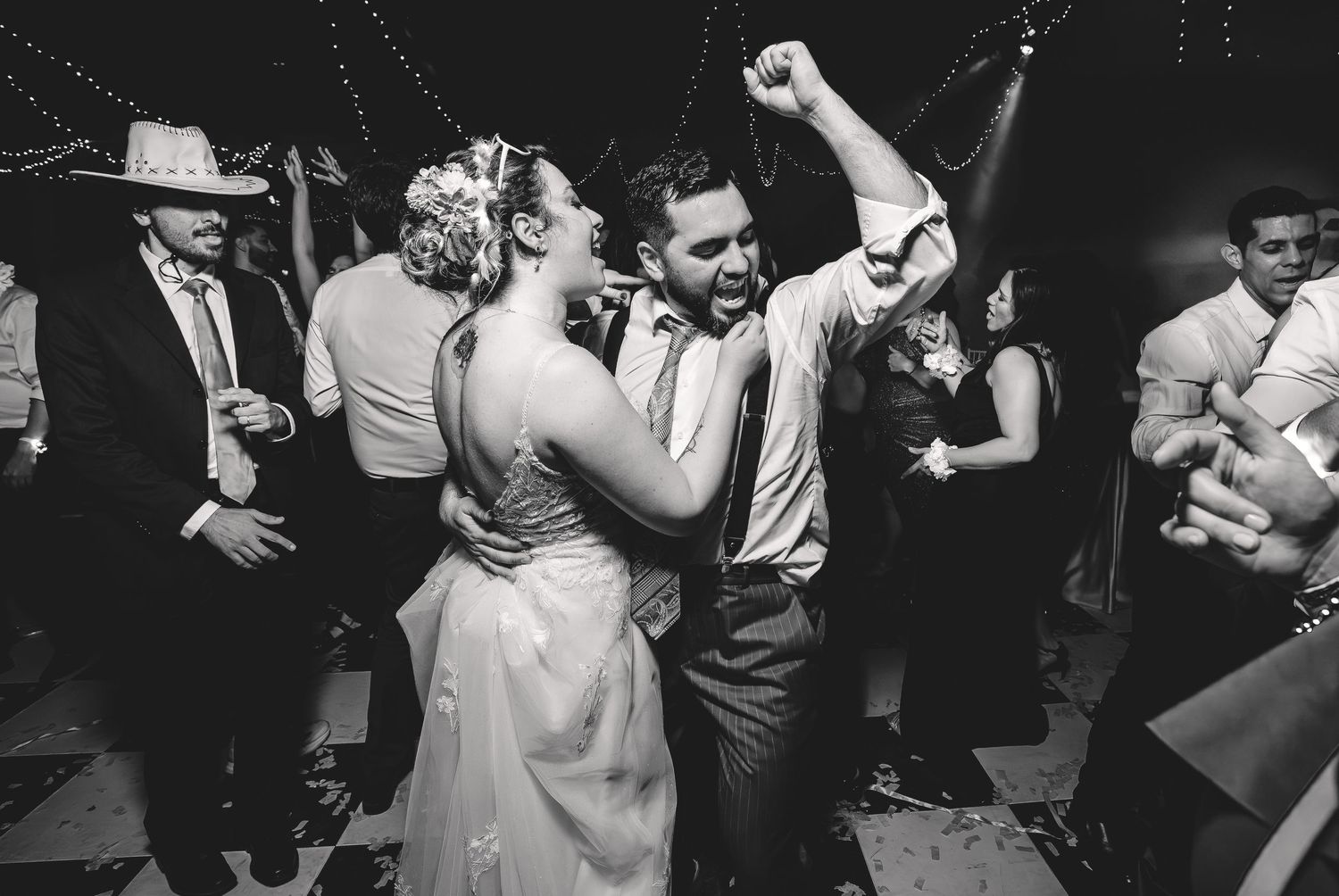 Black and white photo of bride and groom dancing joyfully at wedding reception.