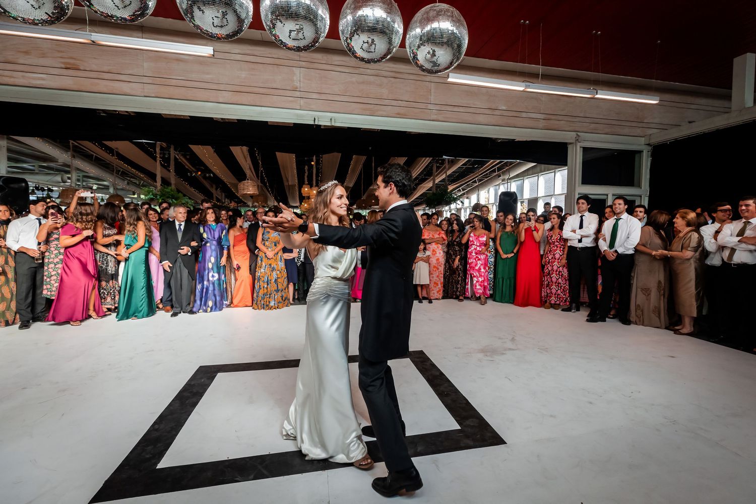 Bride and groom share their first dance on a black and white dance floor.
