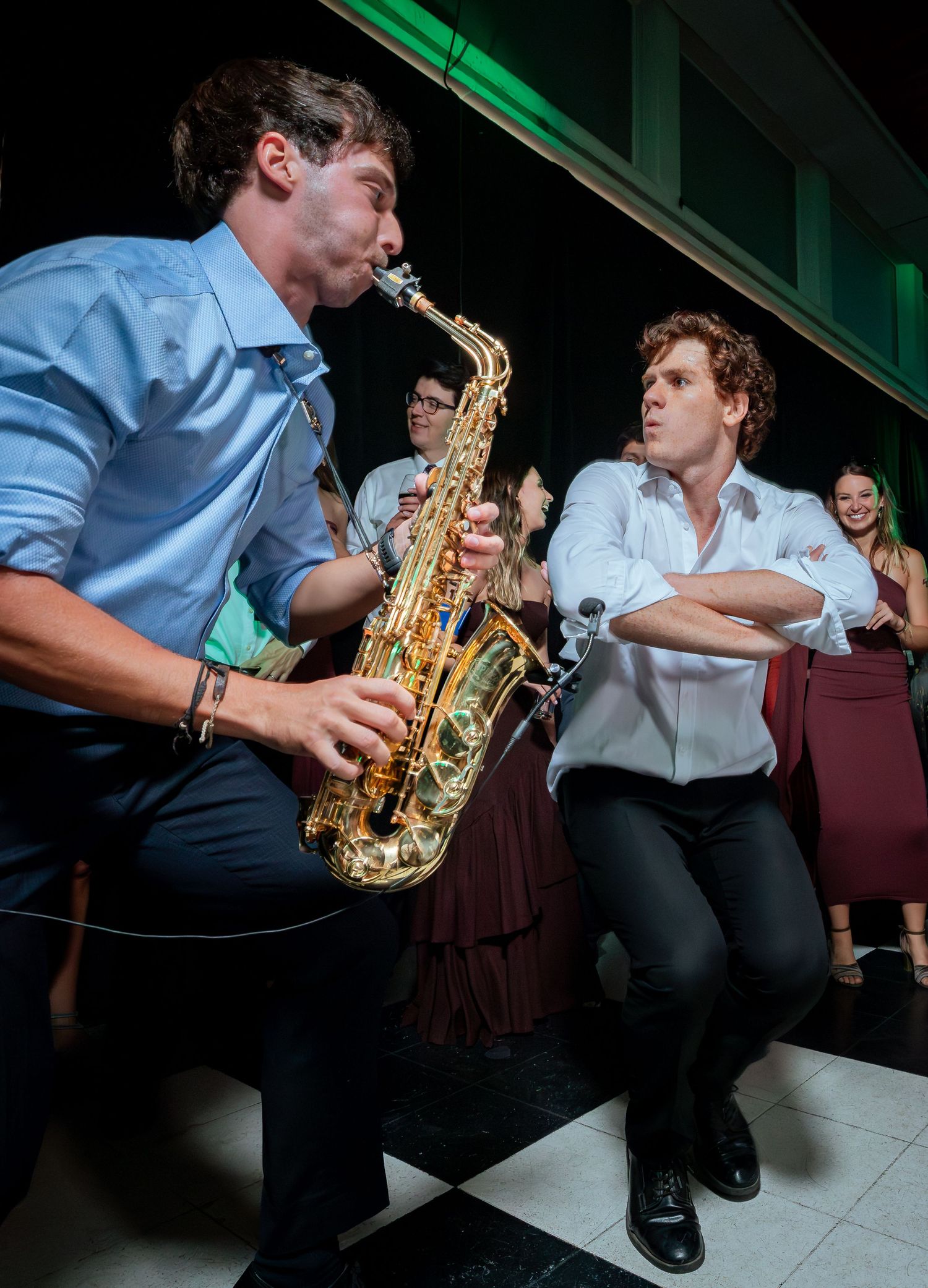 Saxophonist performs energetically face-to-face with dancing guest at lively wedding reception.