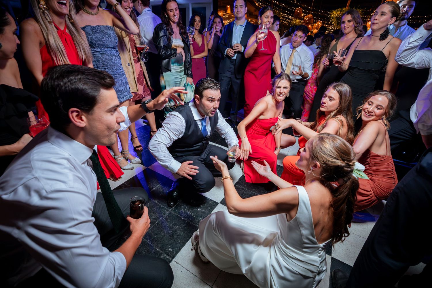 Bride and groom dance with guests in a lively circle on the wedding reception dance floor.