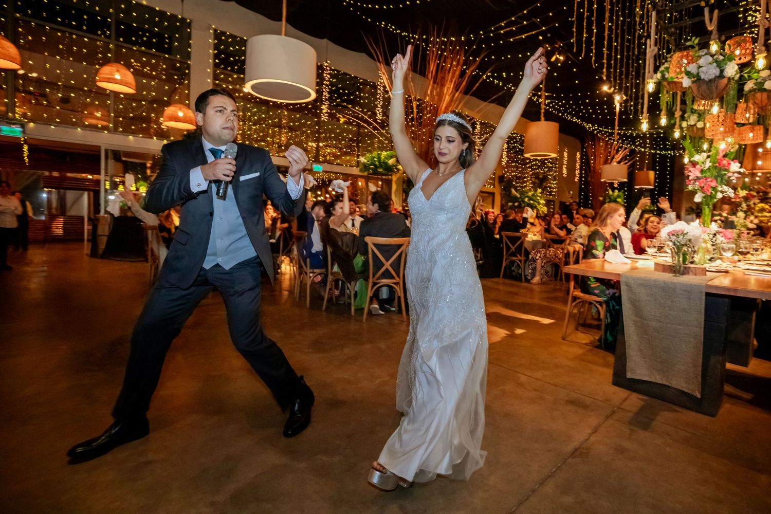 Bride and groom making a grand entrance at their wedding reception with fairy light backdrop.
