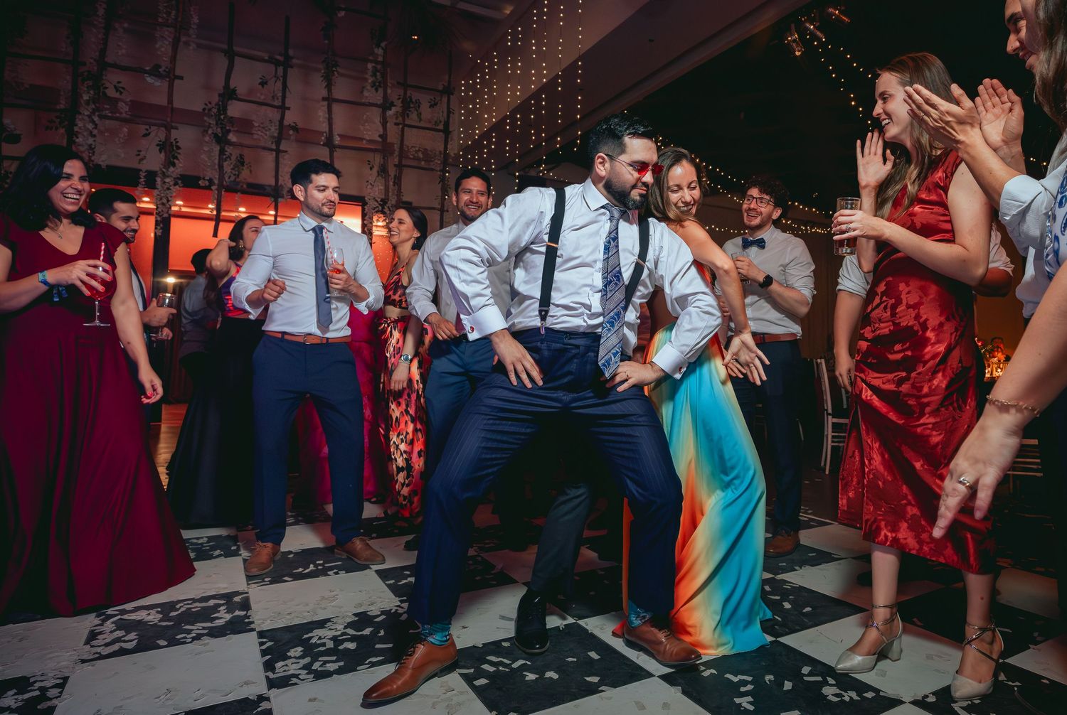 Energetic guest performs fun dance moves on a black and white wedding reception floor.